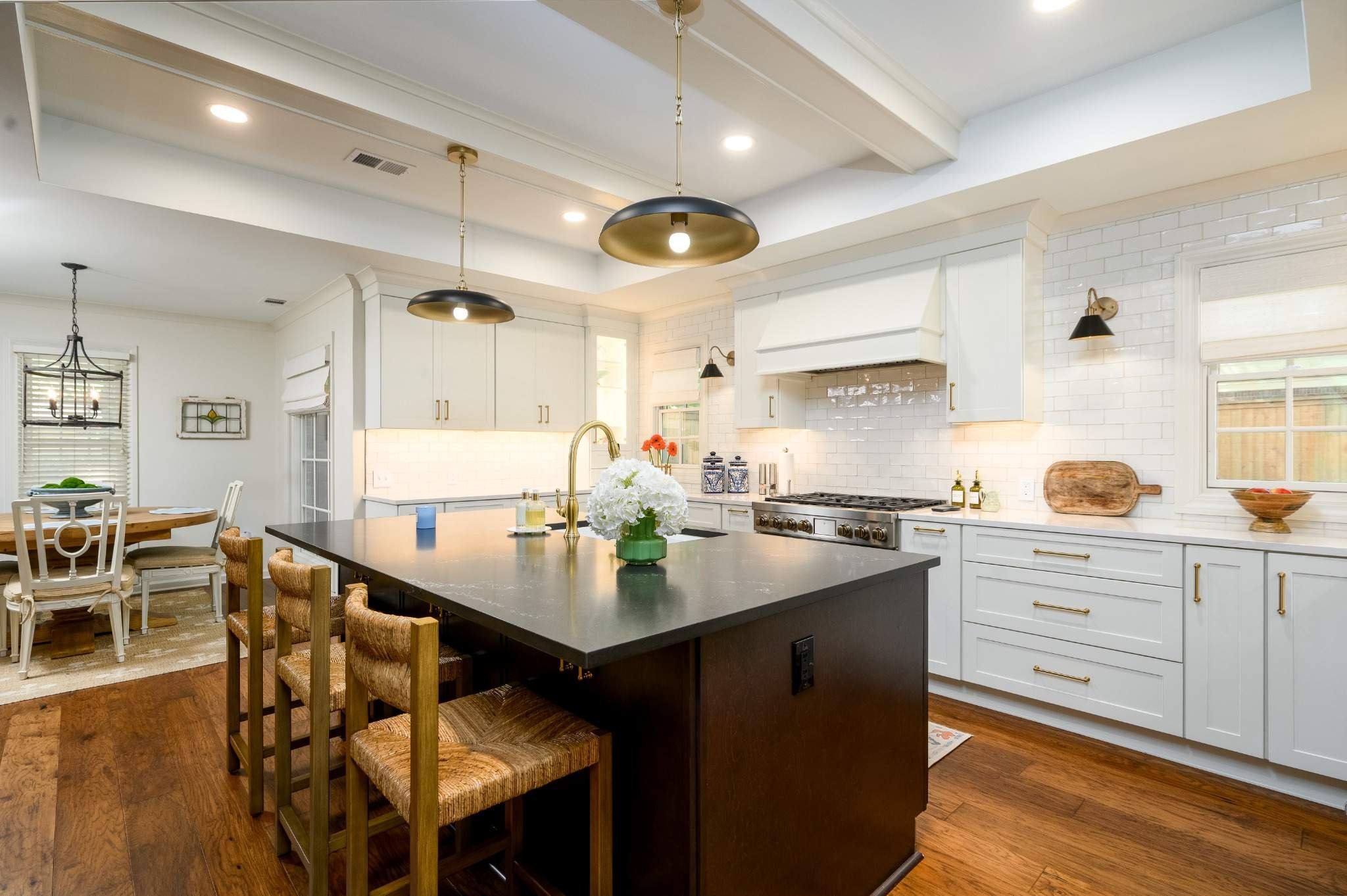 Bright East Memphis kitchen remodel featuring custom white cabinetry, brass hardware, white countertops and warm hardwood floors.