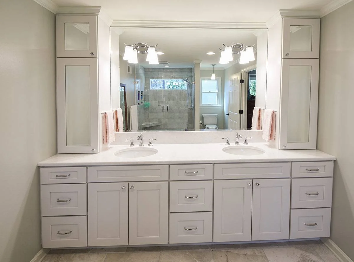 A bright and spacious primary bathroom featuring a double vanity, custom cabinetry, and a clean, neutral design palette.