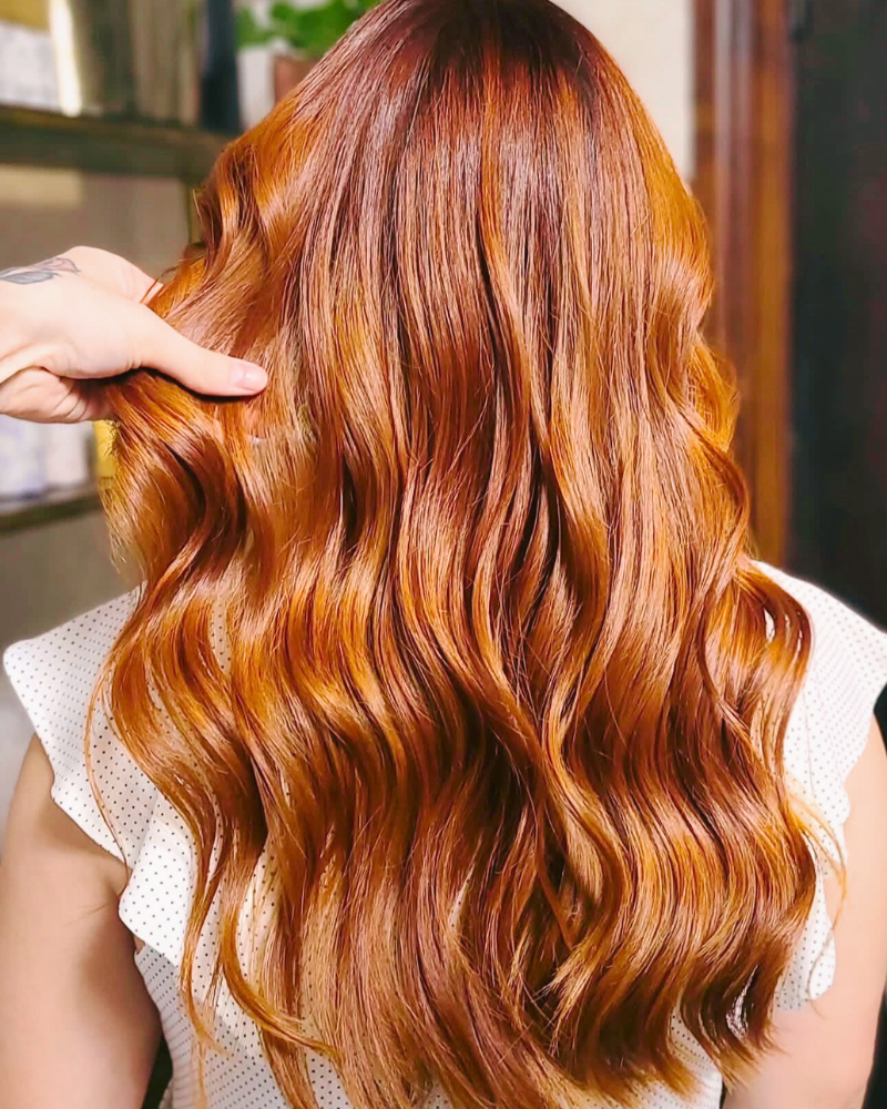 Close-up of a person with long, wavy, reddish-brown hair.