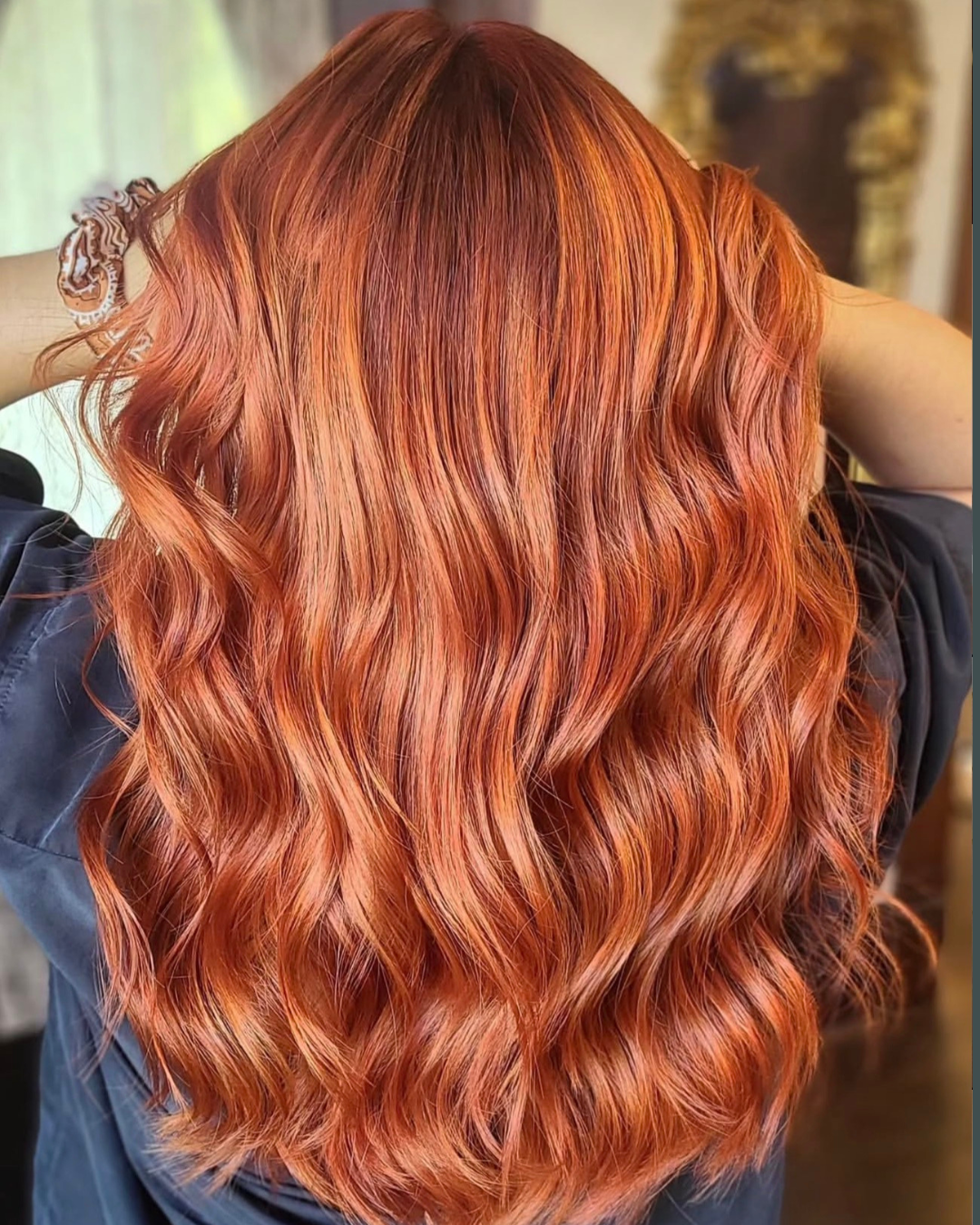 Back view of a person with long, wavy, vibrant red hair.