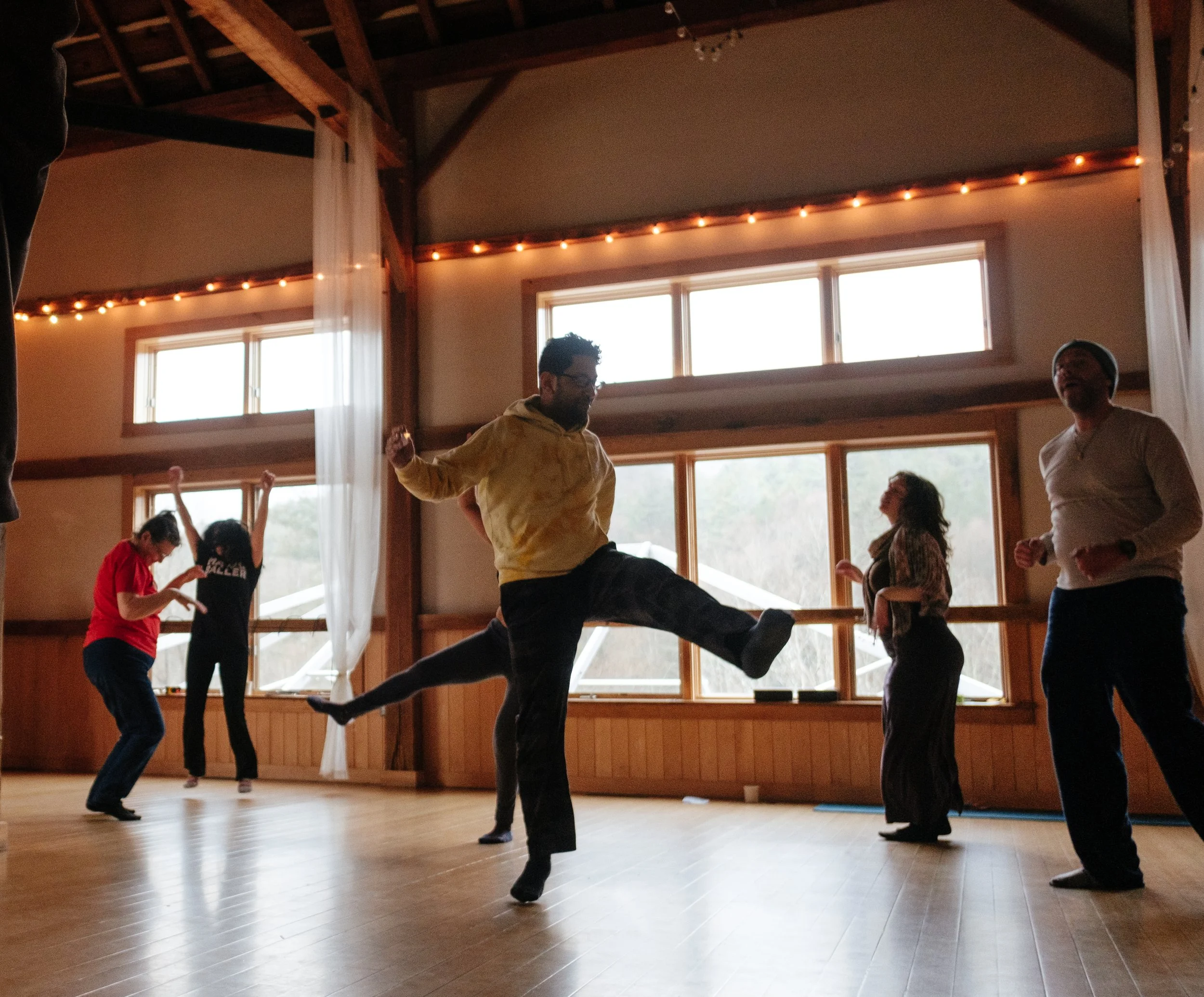 Participants moving with extended arms in a wooden studio.