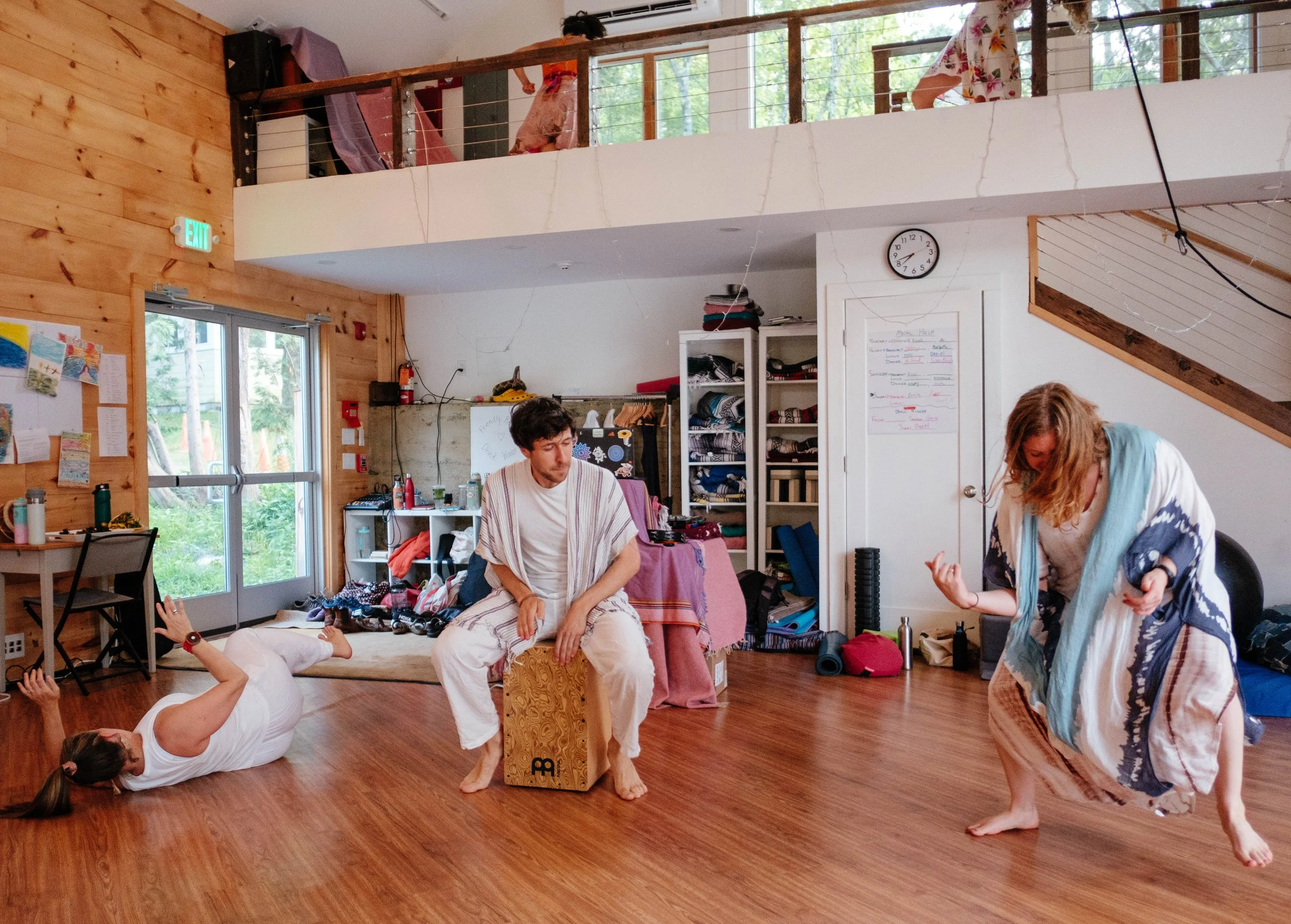 People gathered around the edge of a bright wooden room.