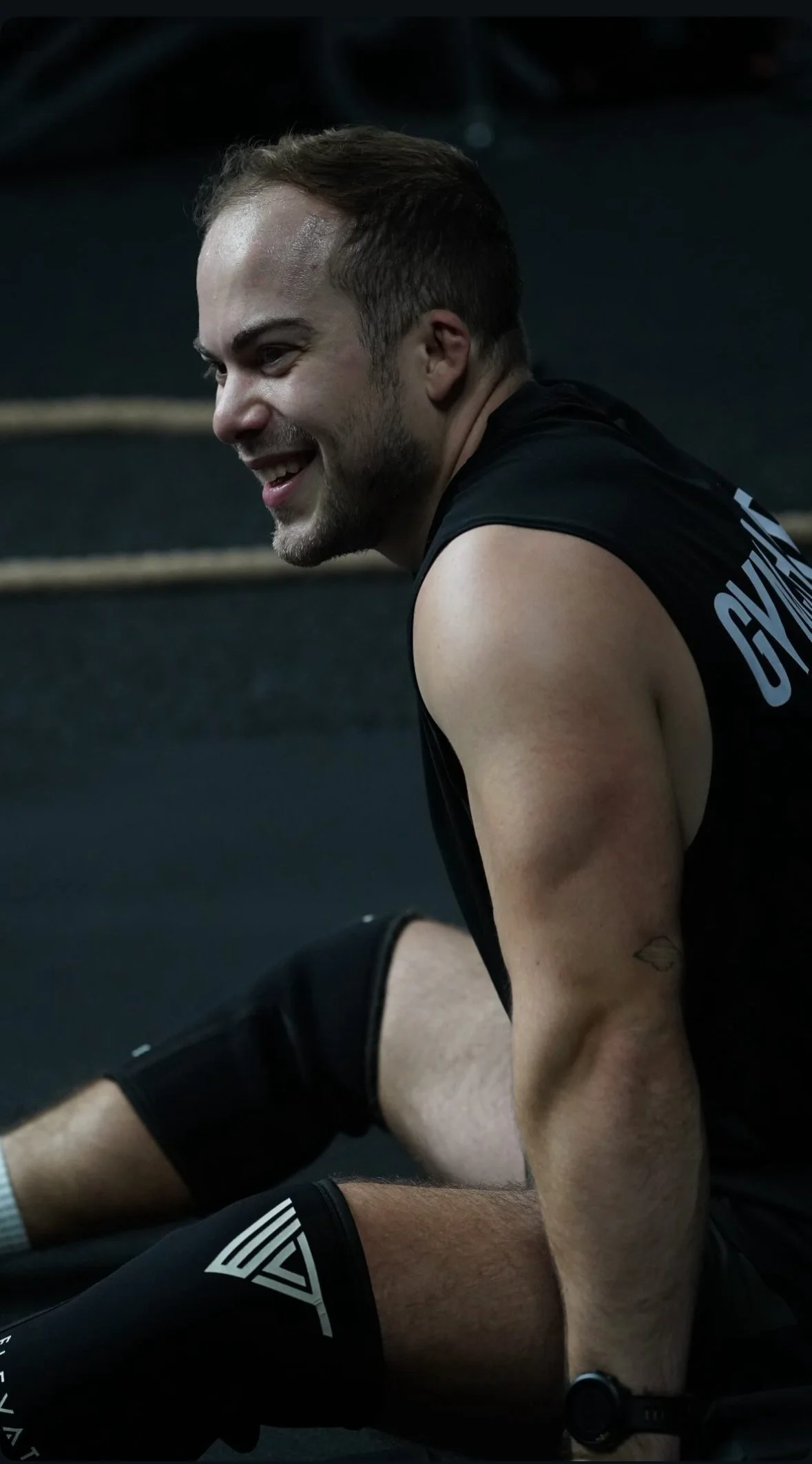 A young man smiling during a workout or exercise session at a gym.