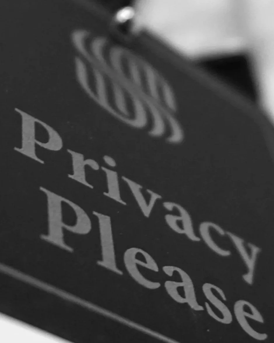 Close-up of a black sign with the words "Privacy Please" in white text.