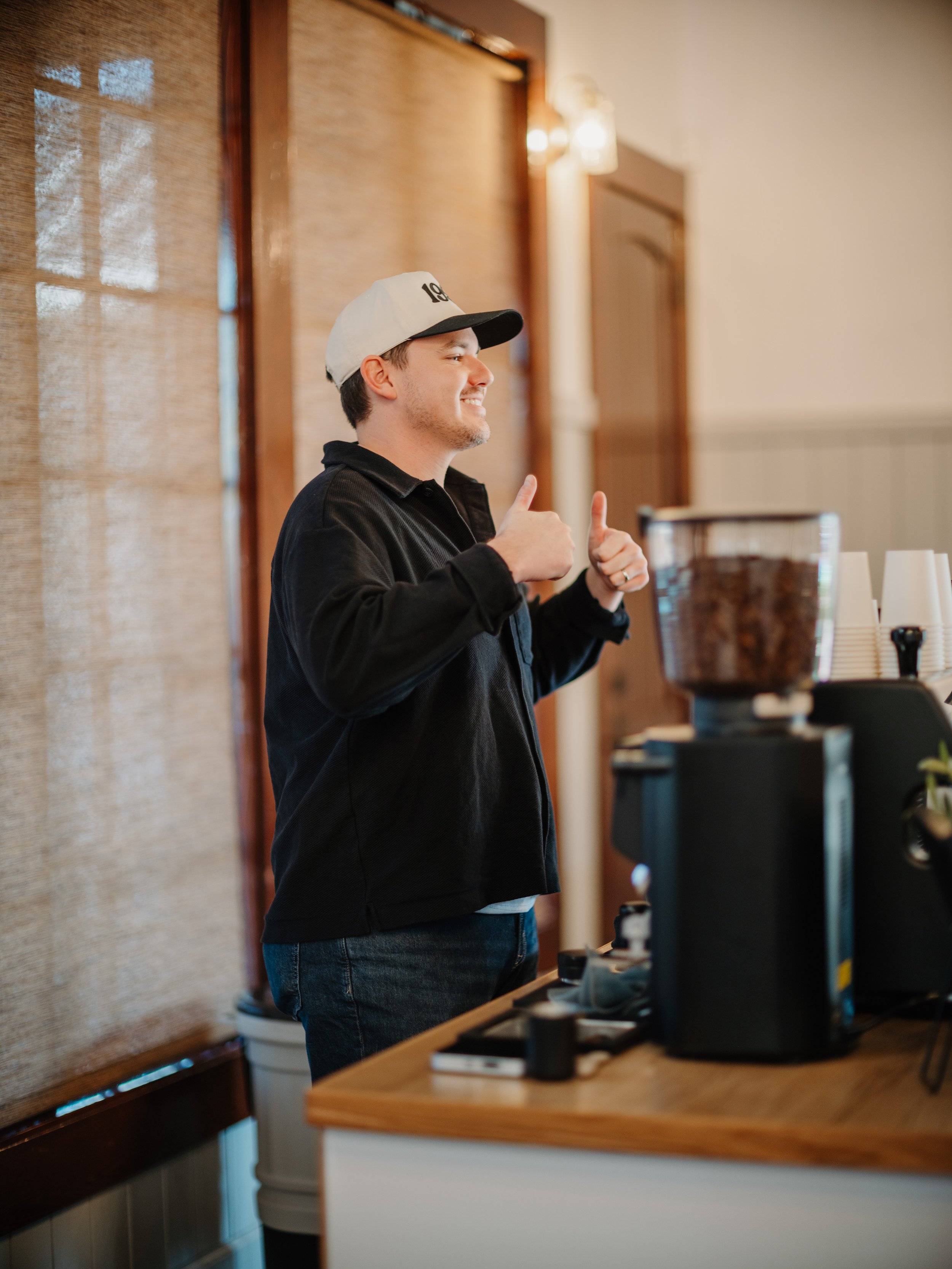 barista smiling behind mobile coffee cart while holding both thumbs up