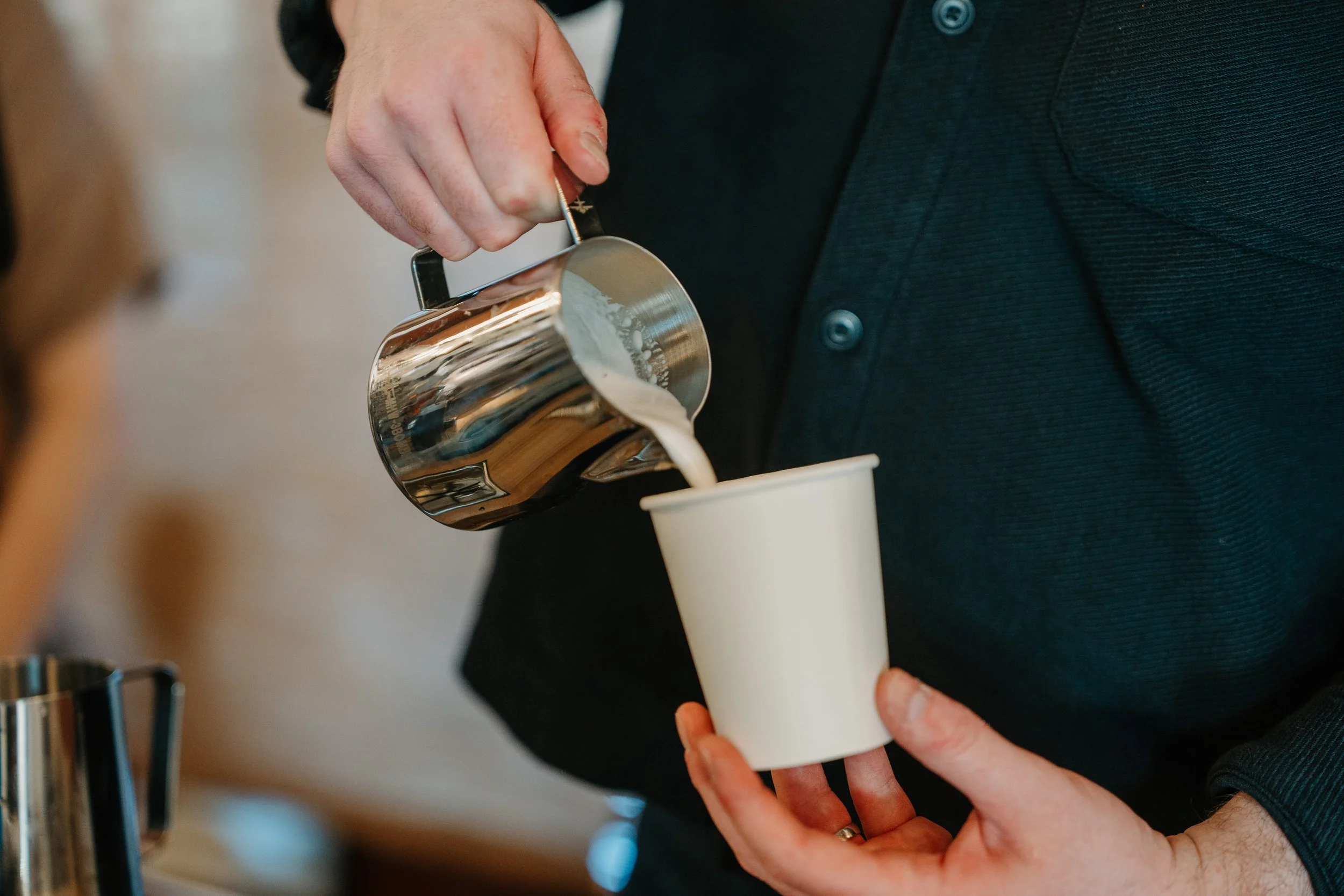 Barista pouring hot milk to make a hot latte in san antonio