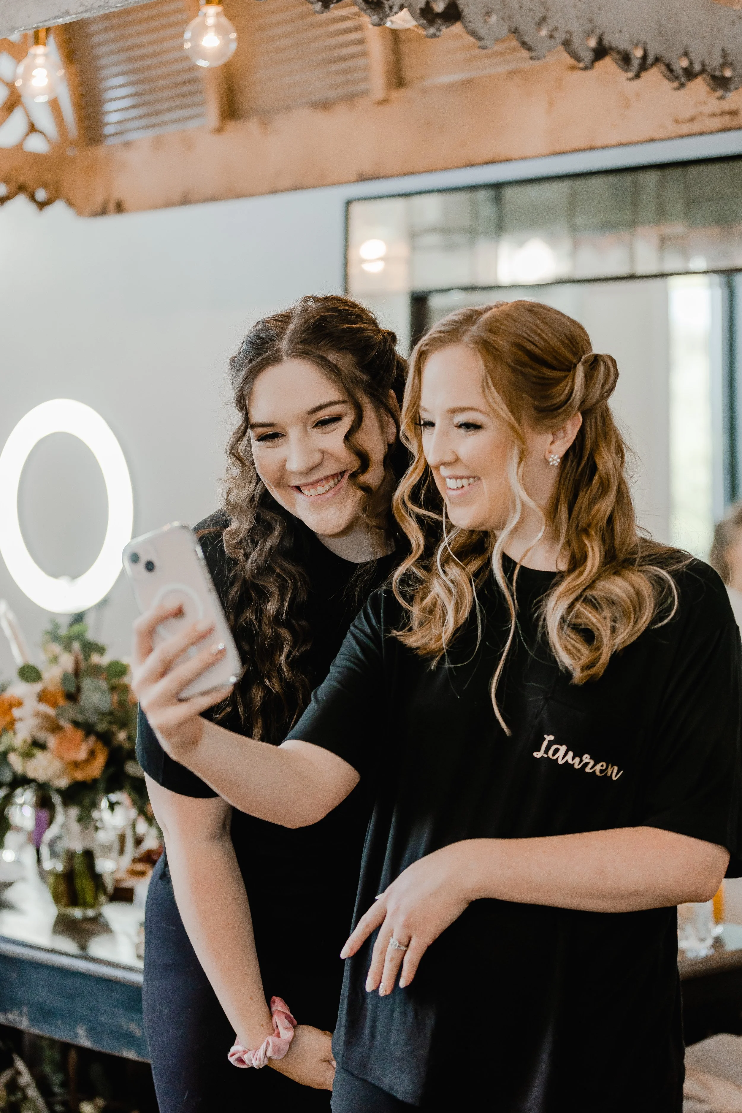 Two women smiling and taking a selfie at a celebration or event, one of them has