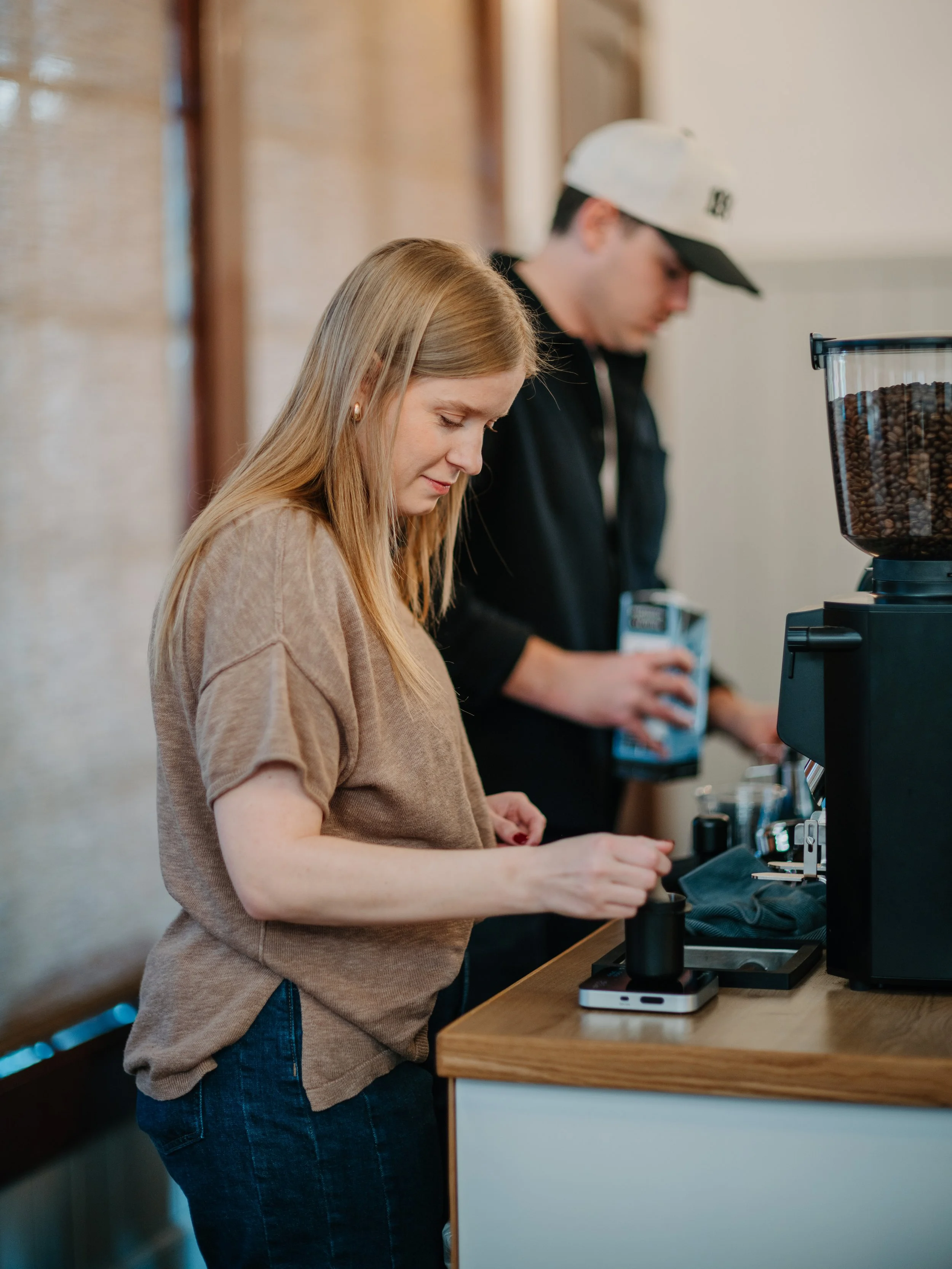 both baristas in action making lattes behind coffee cart