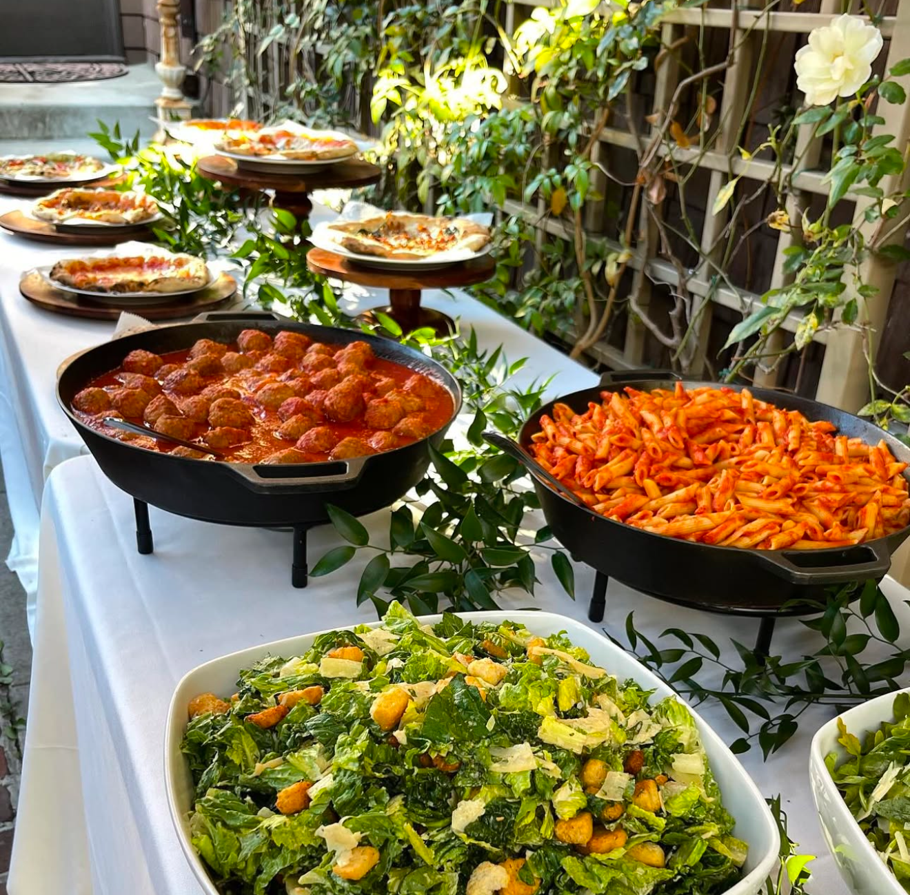 Italian catering buffet with salads, pasta, meatballs, and wood-fired pizza by Olive Wood Pizza