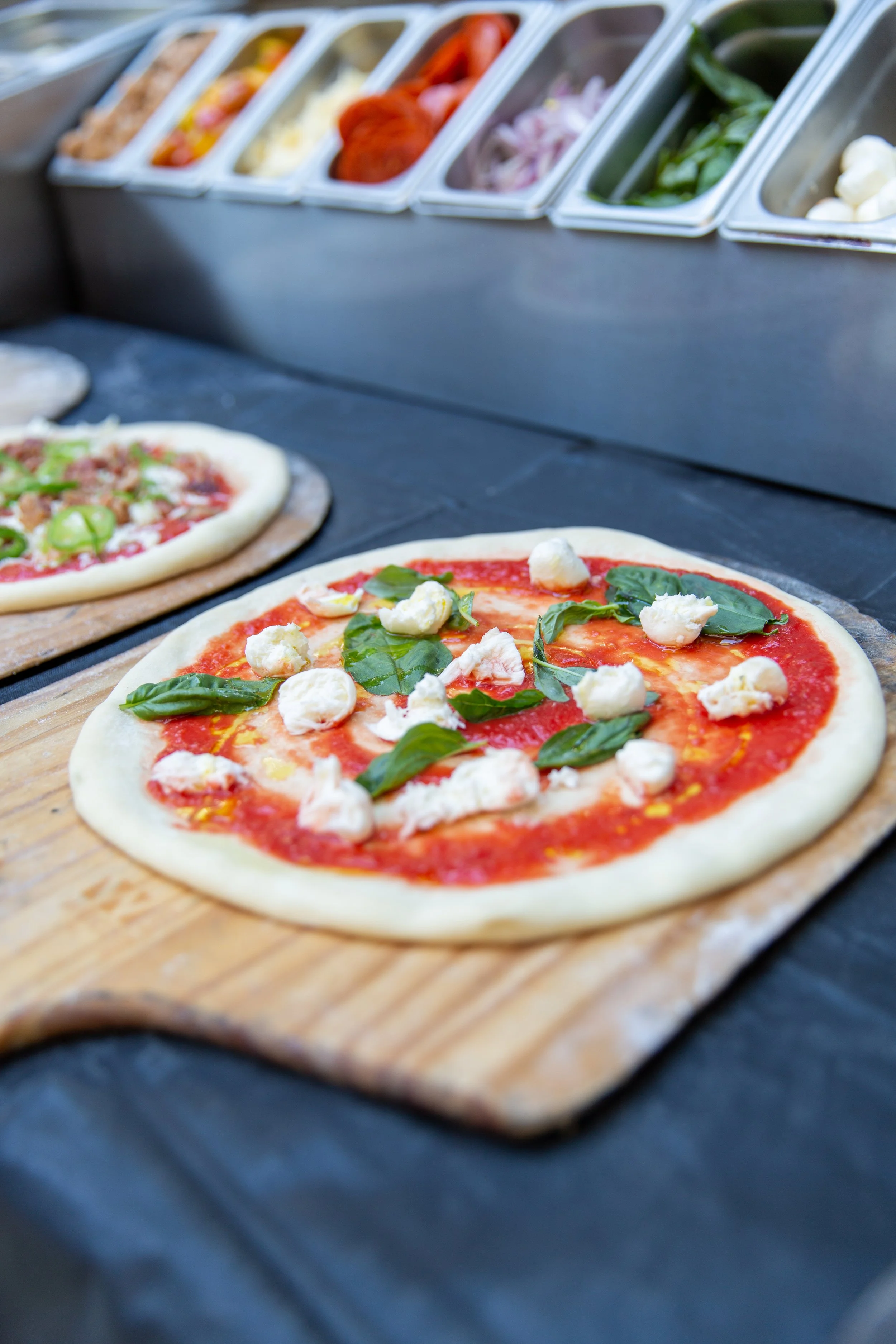 Close-up of a margherita pizza with tomato sauce, fresh basil leaves, and mozzarella cheese on a wooden pizza peel.