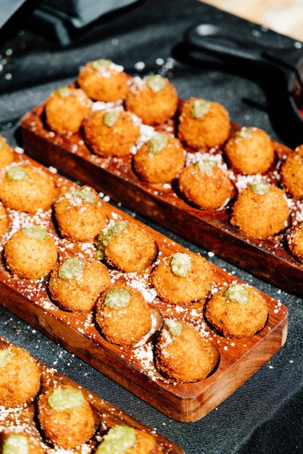 Crispy arancini served on wooden trays at an Olive Wood Pizza catering event