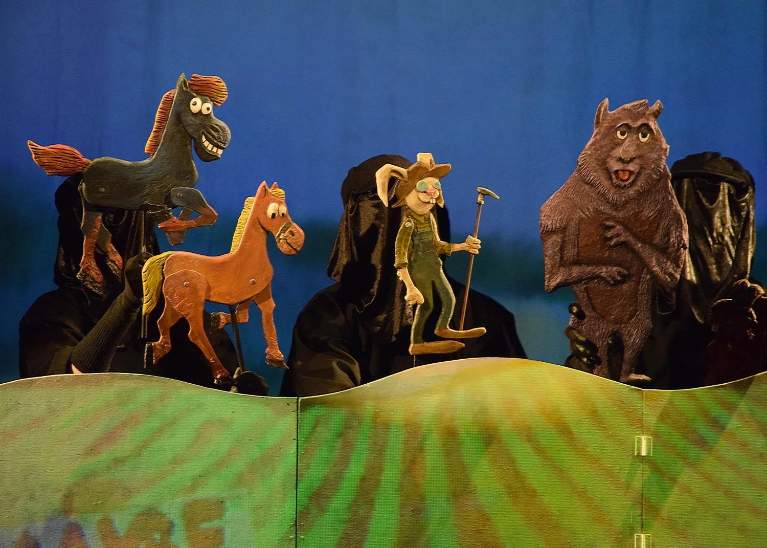 Puppet characters from the TV show 'The Wooden Buffalo' on a stage with a green and yellow background, including a horse, a pig, a rabbit, and a bear.