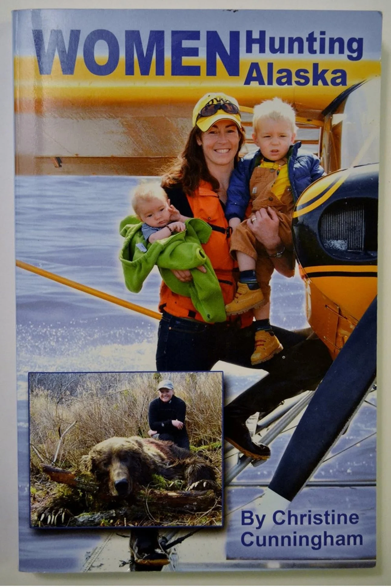 Book cover titled 'Women Hunting Alaska' by Christine Cunningham, showing a woman with two young children on a seaplane and a smaller inset photo of a woman in a black jacket and cap with a bear in the wilderness.