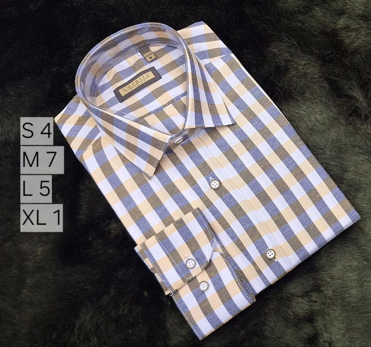 Folded checked men's dress shirt in beige, white, and gray hanging on dark textured background.