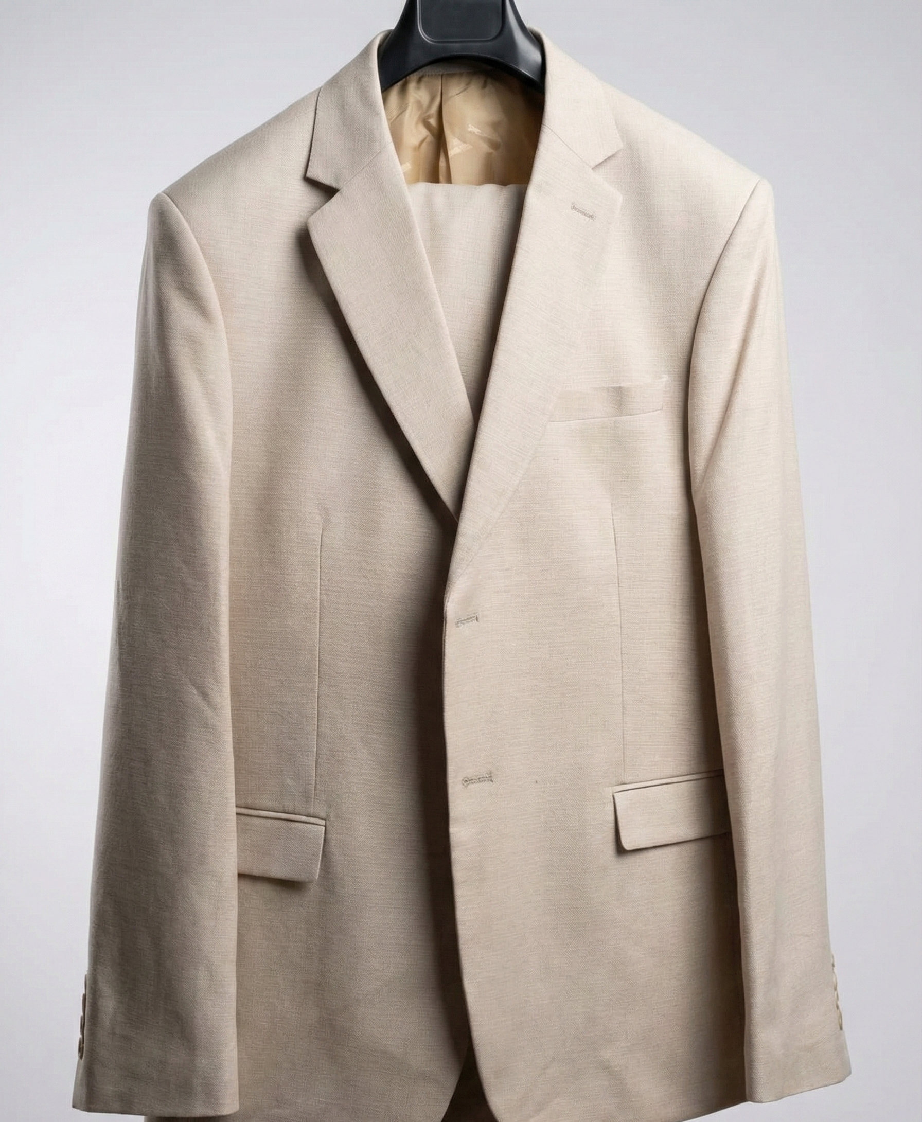 A beige suit jacket hanging on a black hanger against a white background.