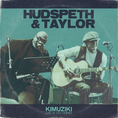 Albumcover von Hudspeth & Taylor mit den Künstlern, einem Mann mit Brille und einem Musiker mit Gitarre, vor einem Mikrofon, beim Live-Auftritt in Des Moines.