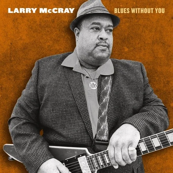 Schwarz-Weiß-Fotografie eines Mannes mit Hut, der eine Gitarre hält, vor orangefarbenem Hintergrund. Text: arry McCray Blues Without You".