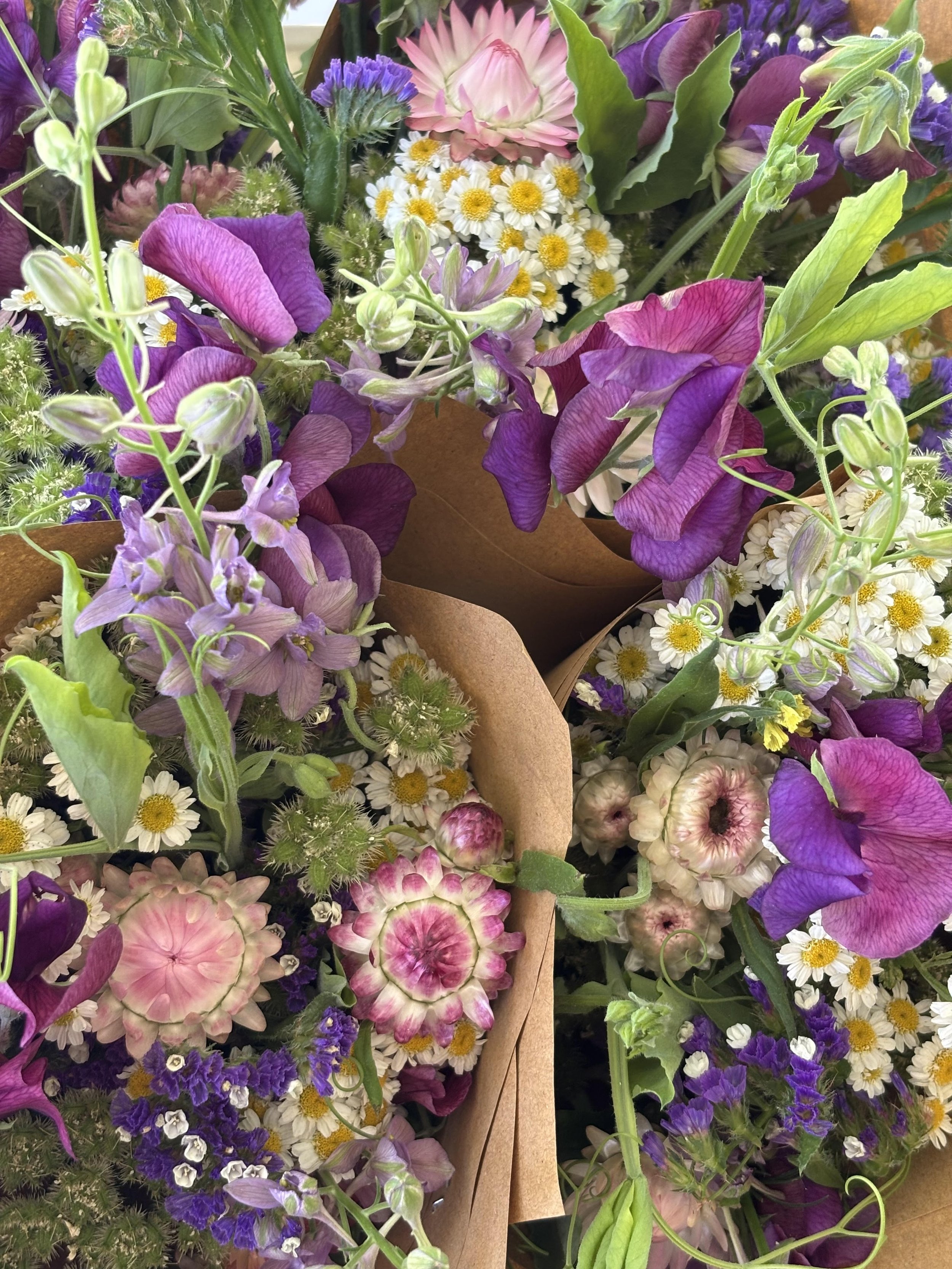 Close-up of various colorful flowers including purple, pink, white, and yellow blooms in bouquets.