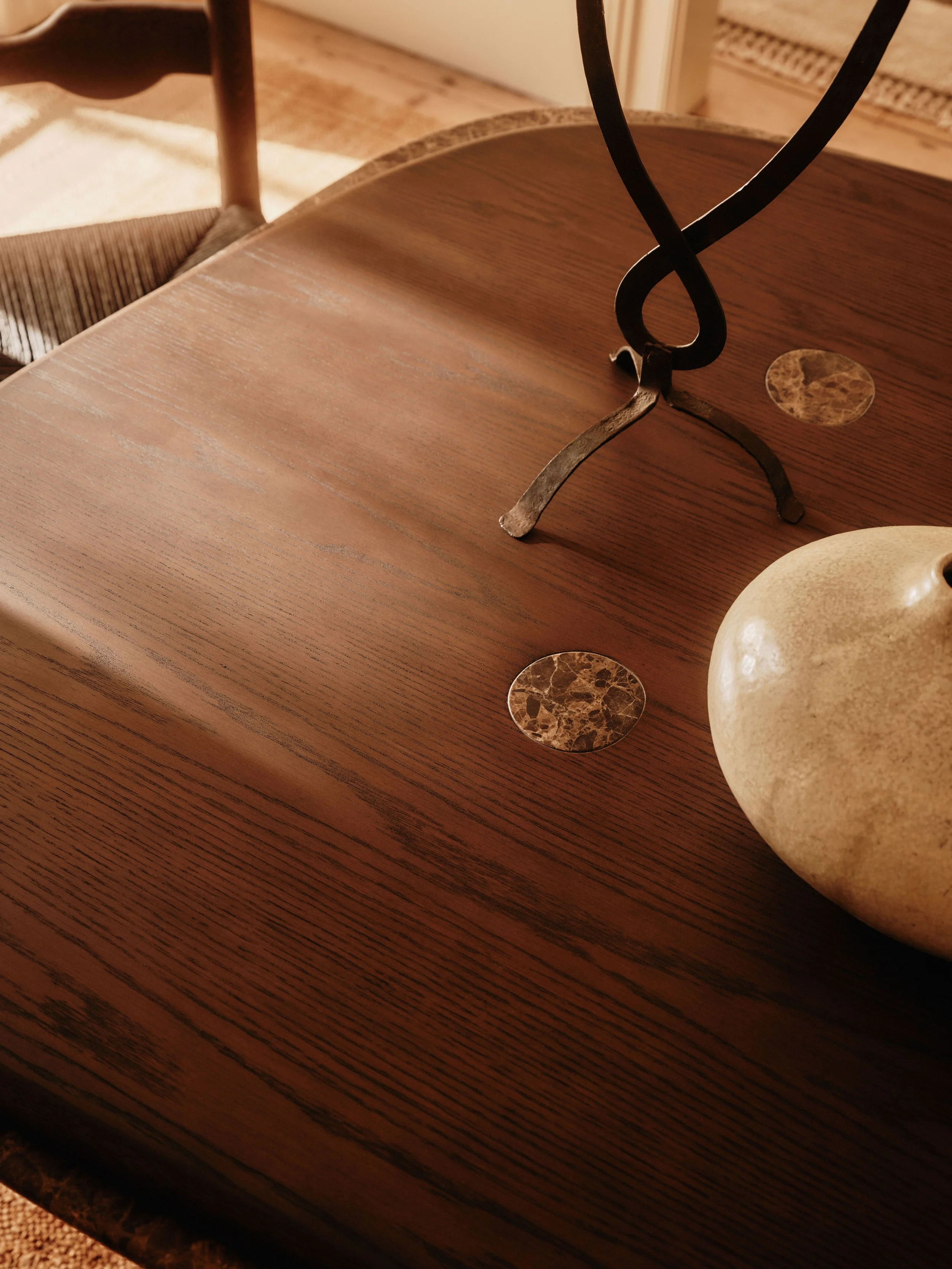 Close-up of a wooden dining table with decorative metal and stone accents.