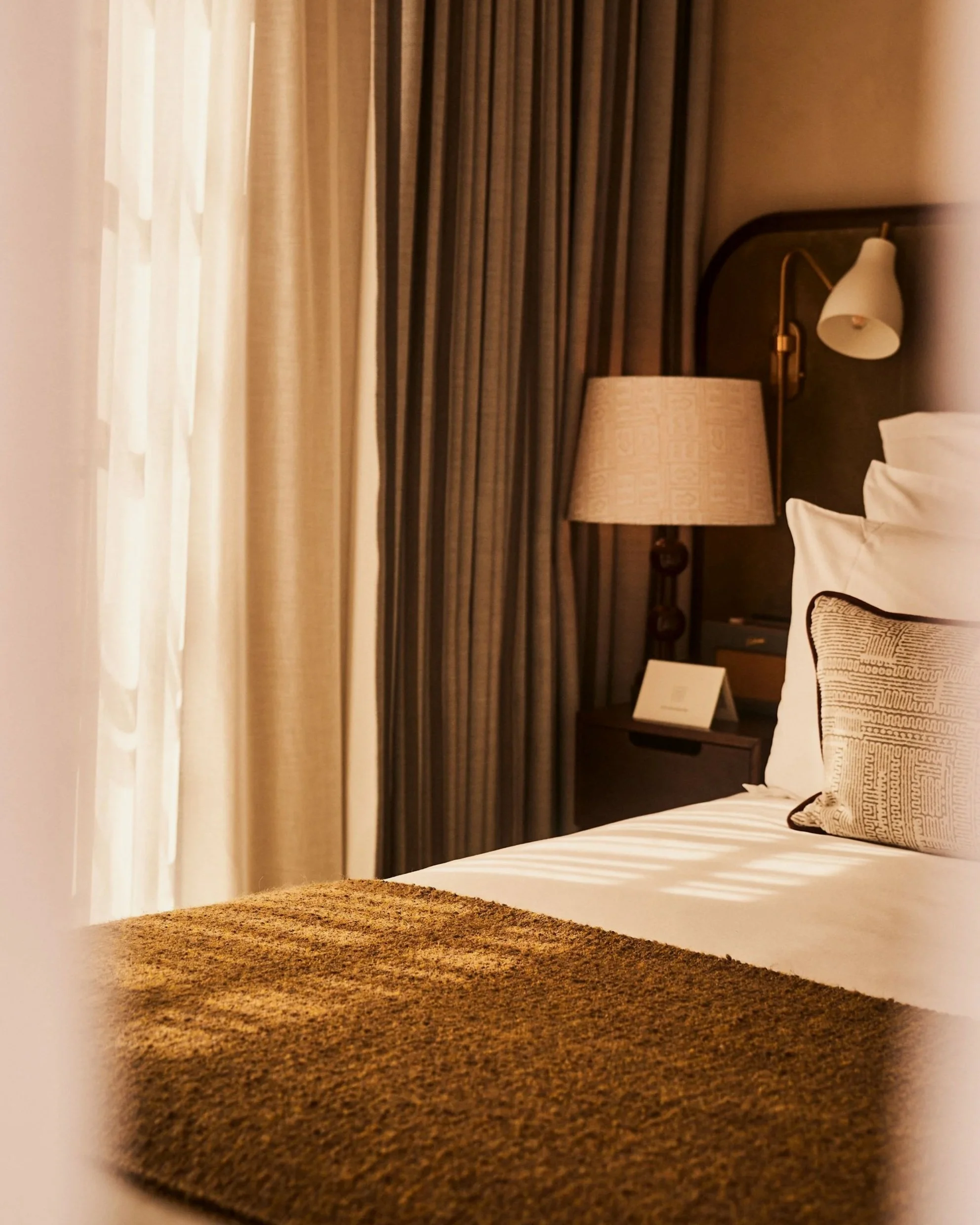 Moody, warm-toned hotel bedroom vignette showcasing rich textiles and dim ambient lighting at Soho House Rome, photography by Ryan Handy.