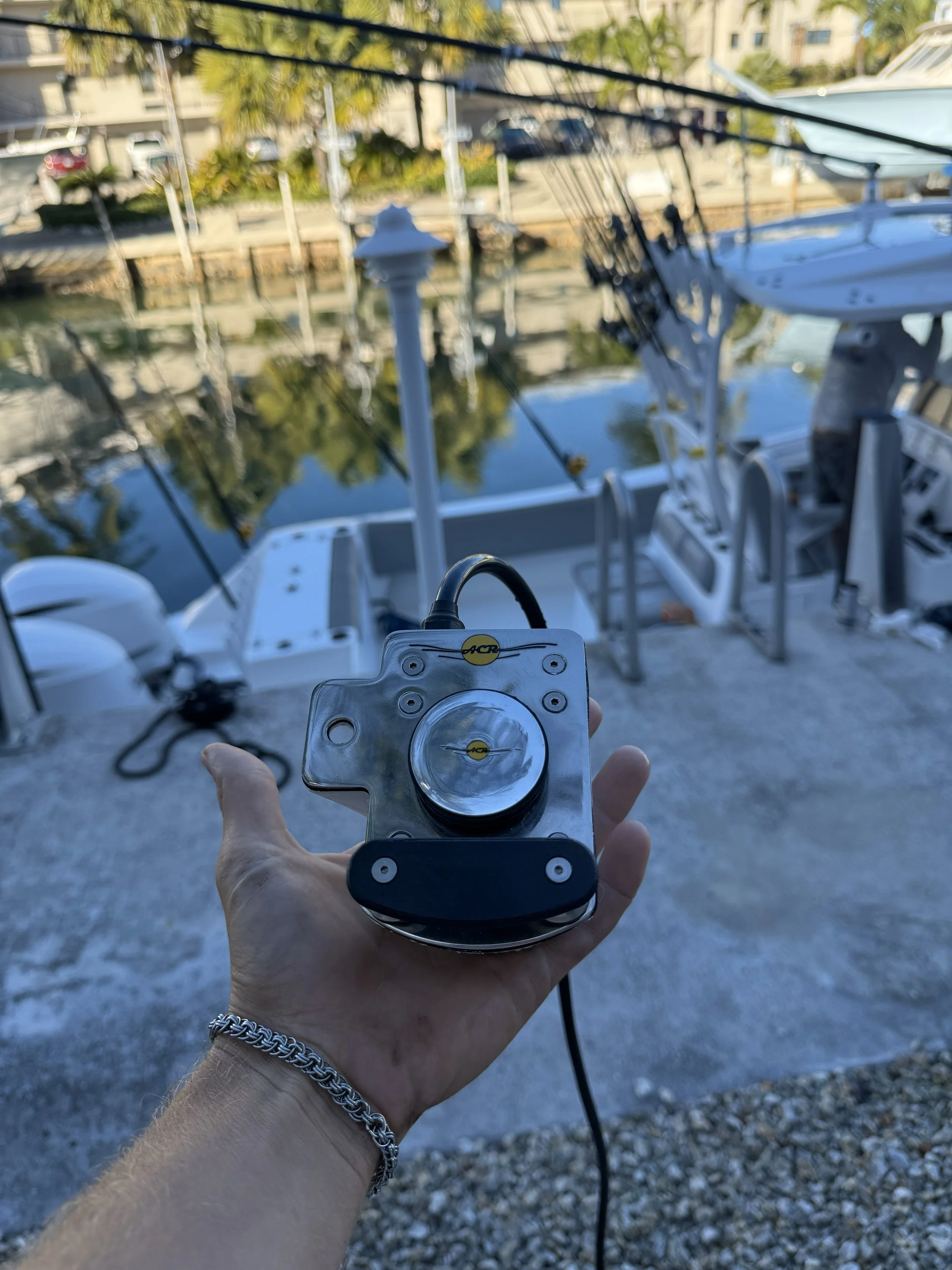 View from a fishing boat with four fishing rods set up. The boat is on the open water, moving away from the viewer, with a clear blue sky overhead.