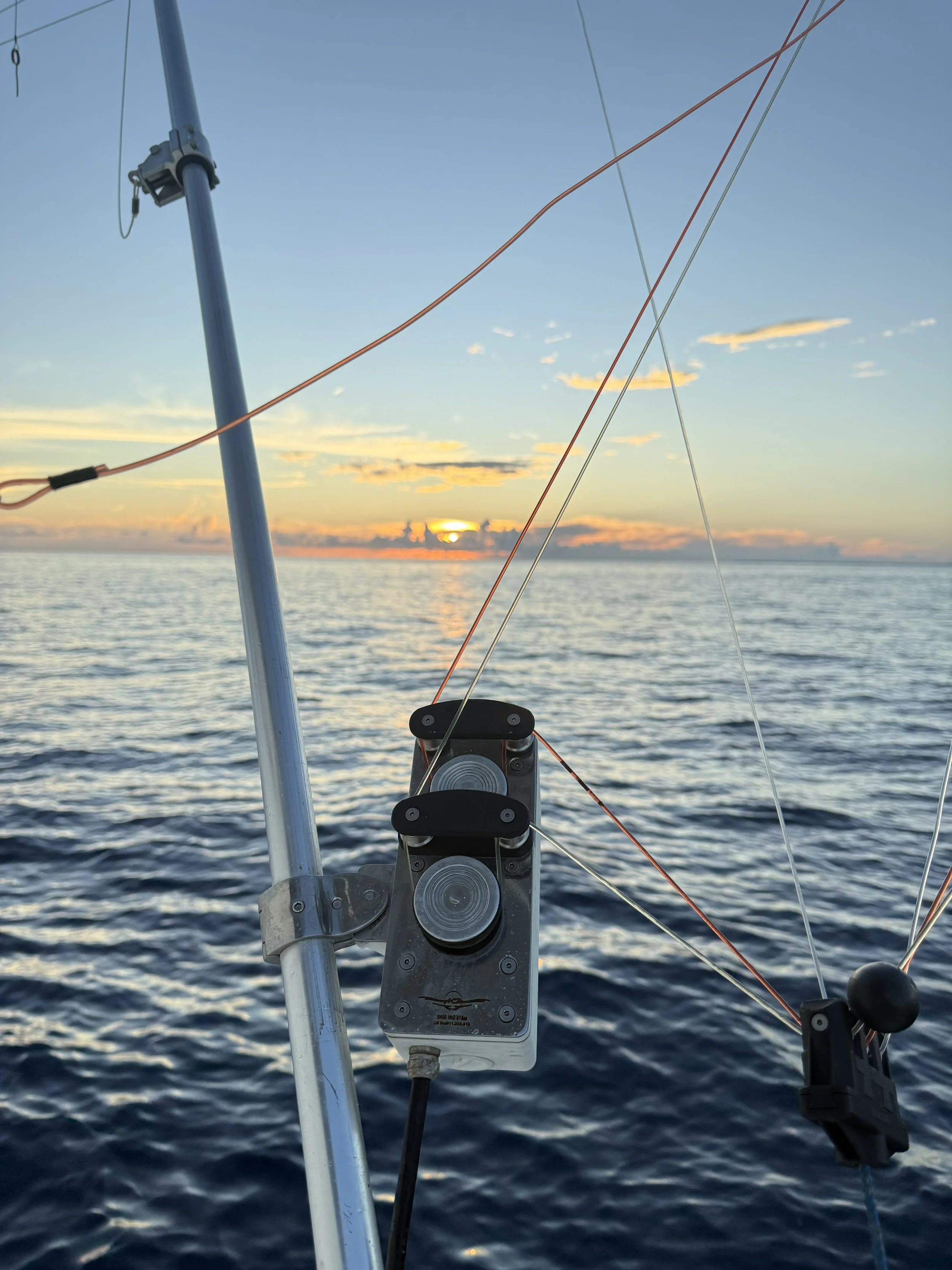 View from a boat showing fishing gear and the ocean at sunset.