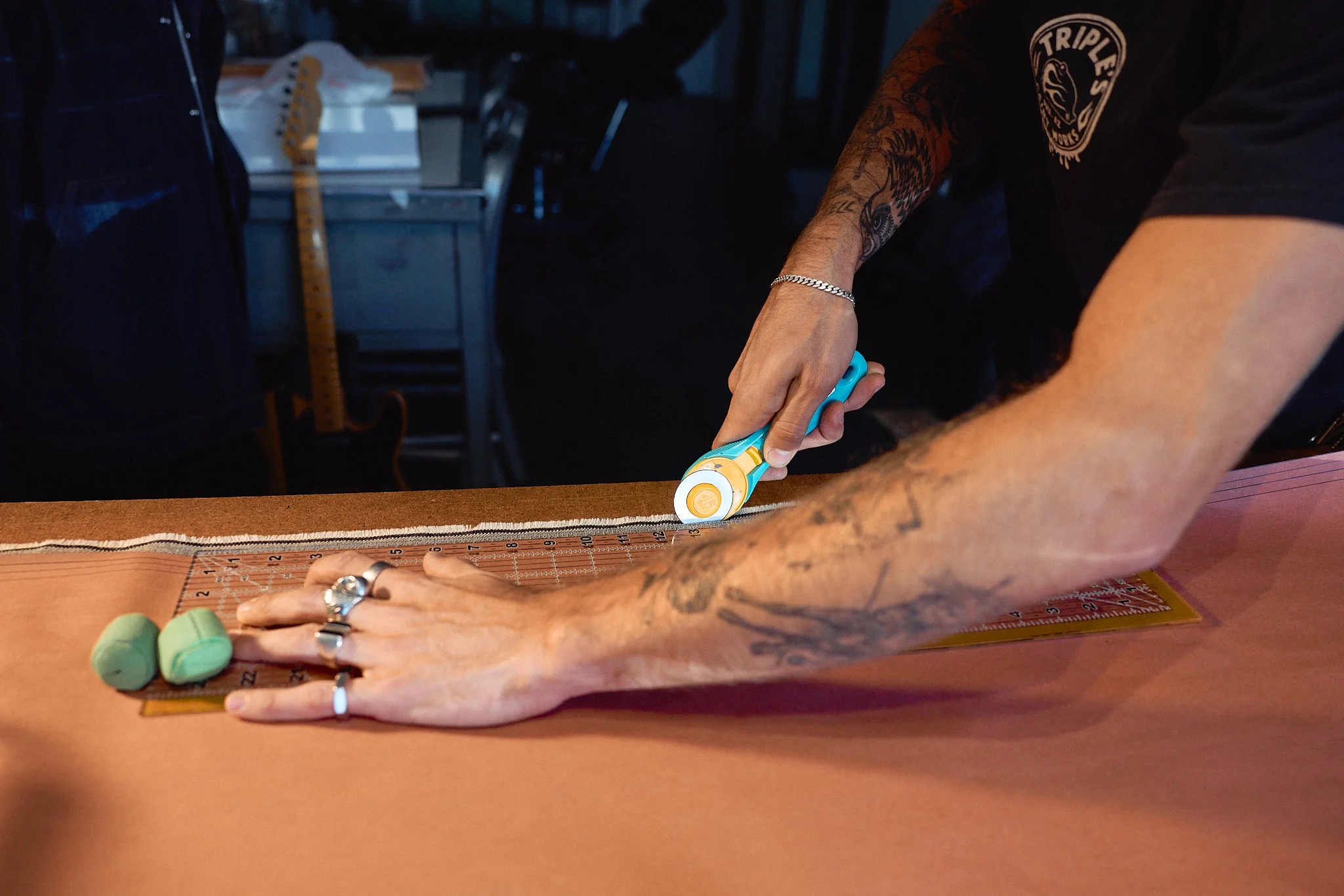 Person measuring fabric with a rotary cutter on cutting mat at a workspace.
