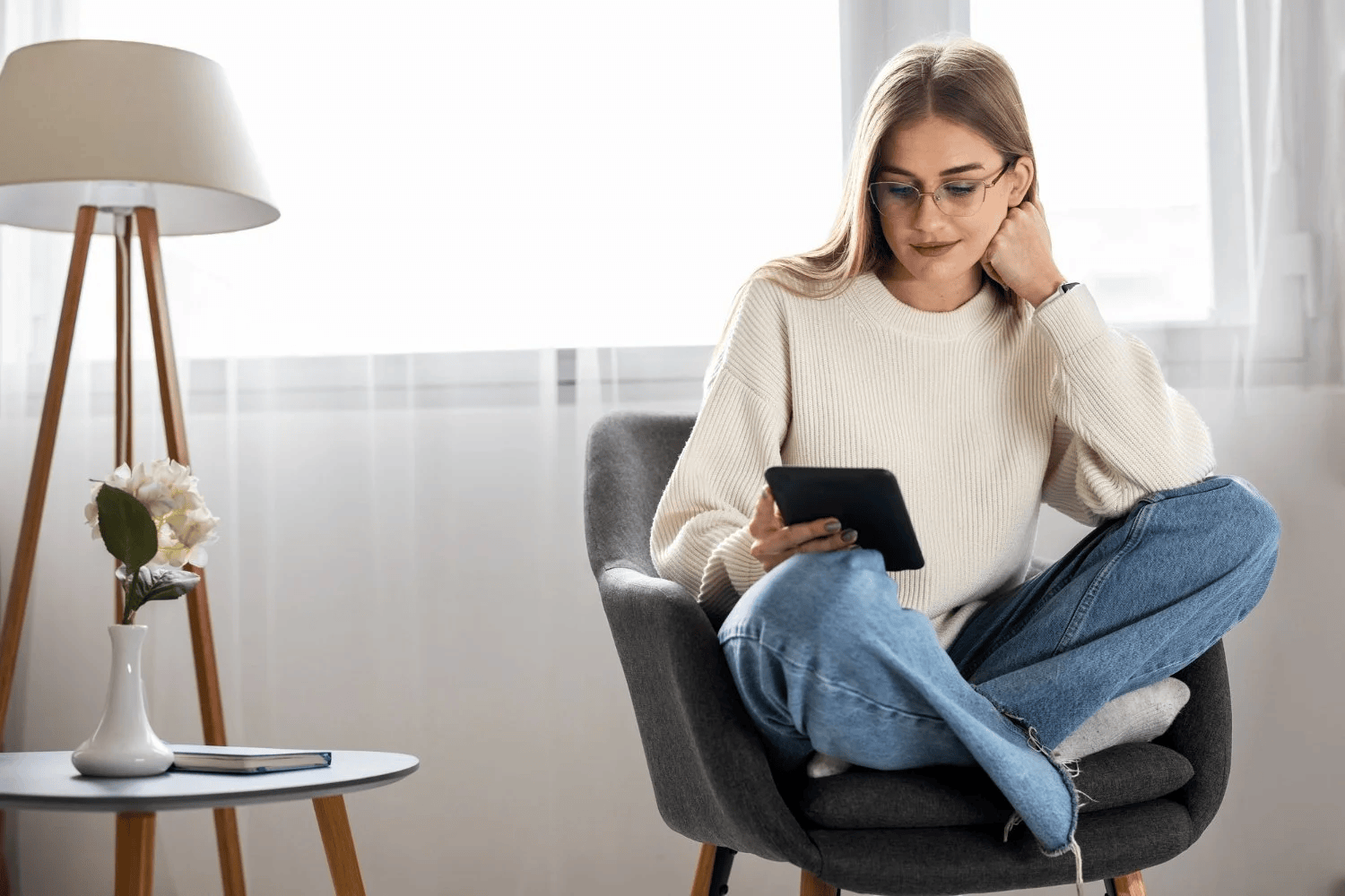 Young woman sitting in a modern living room, looking at her phone.