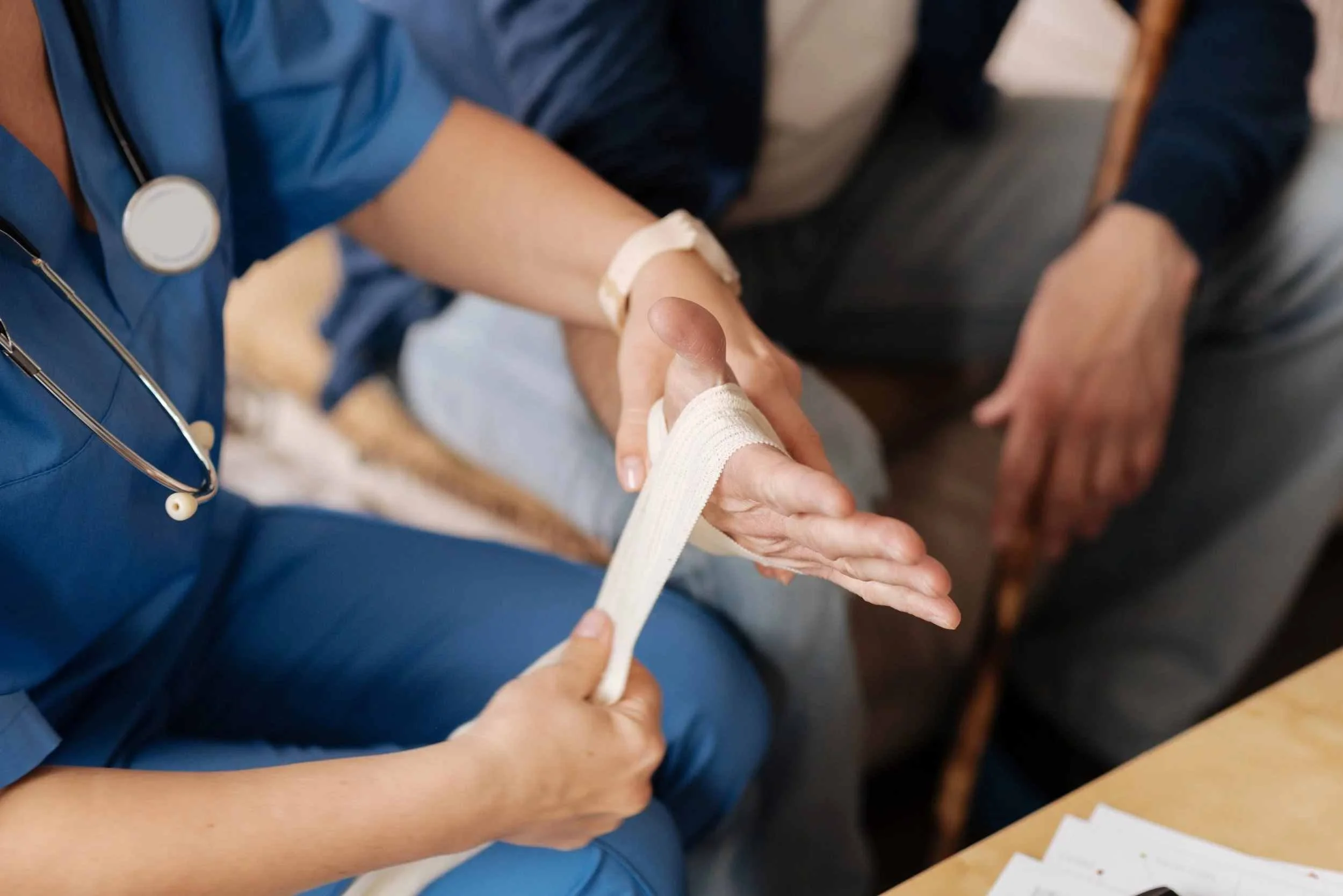 A nurse wrapping a patient's hand with medical tape during a medical consultation.