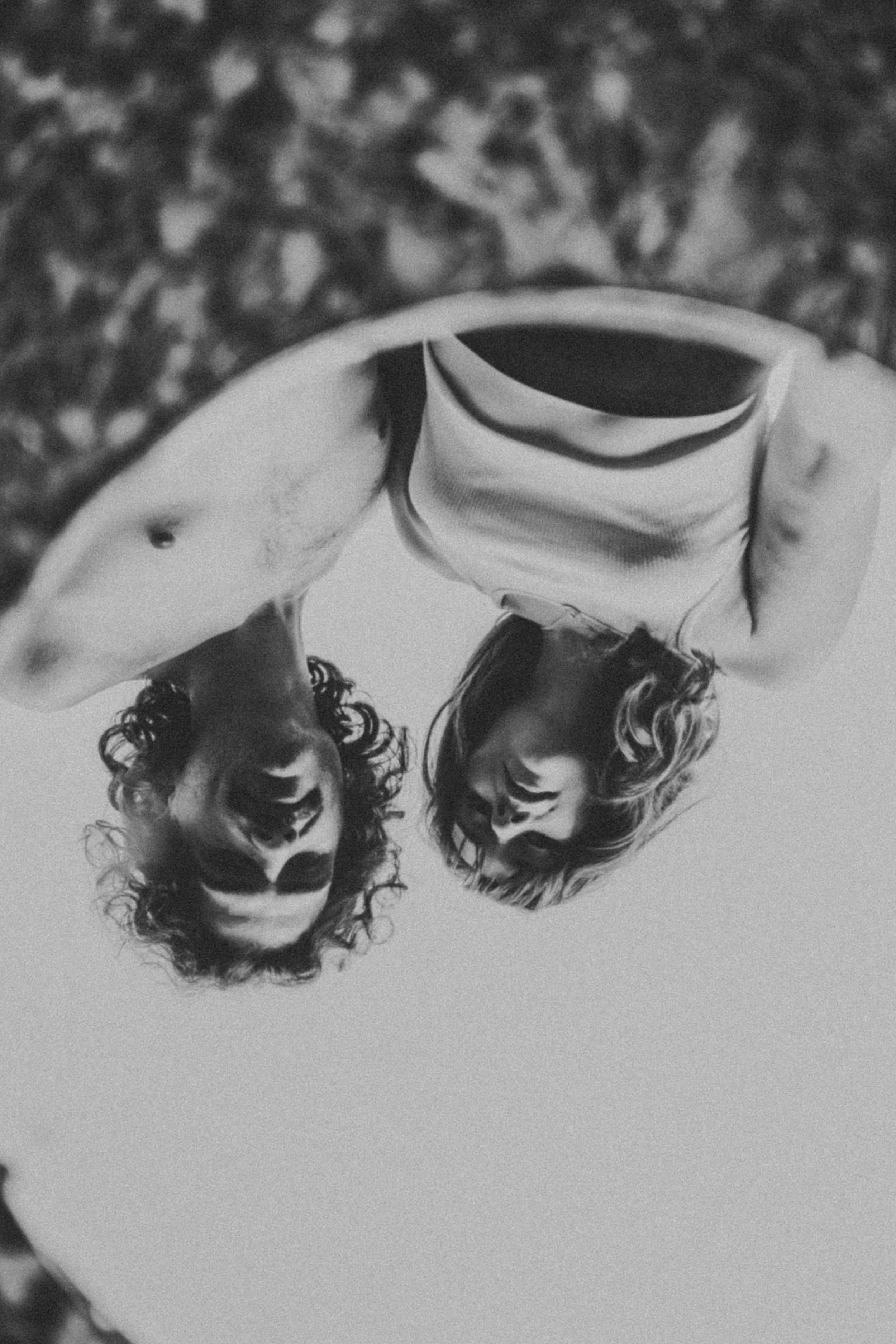 Two women with curly hair looking downward, seen from below, on a circular surface with a blurred background.