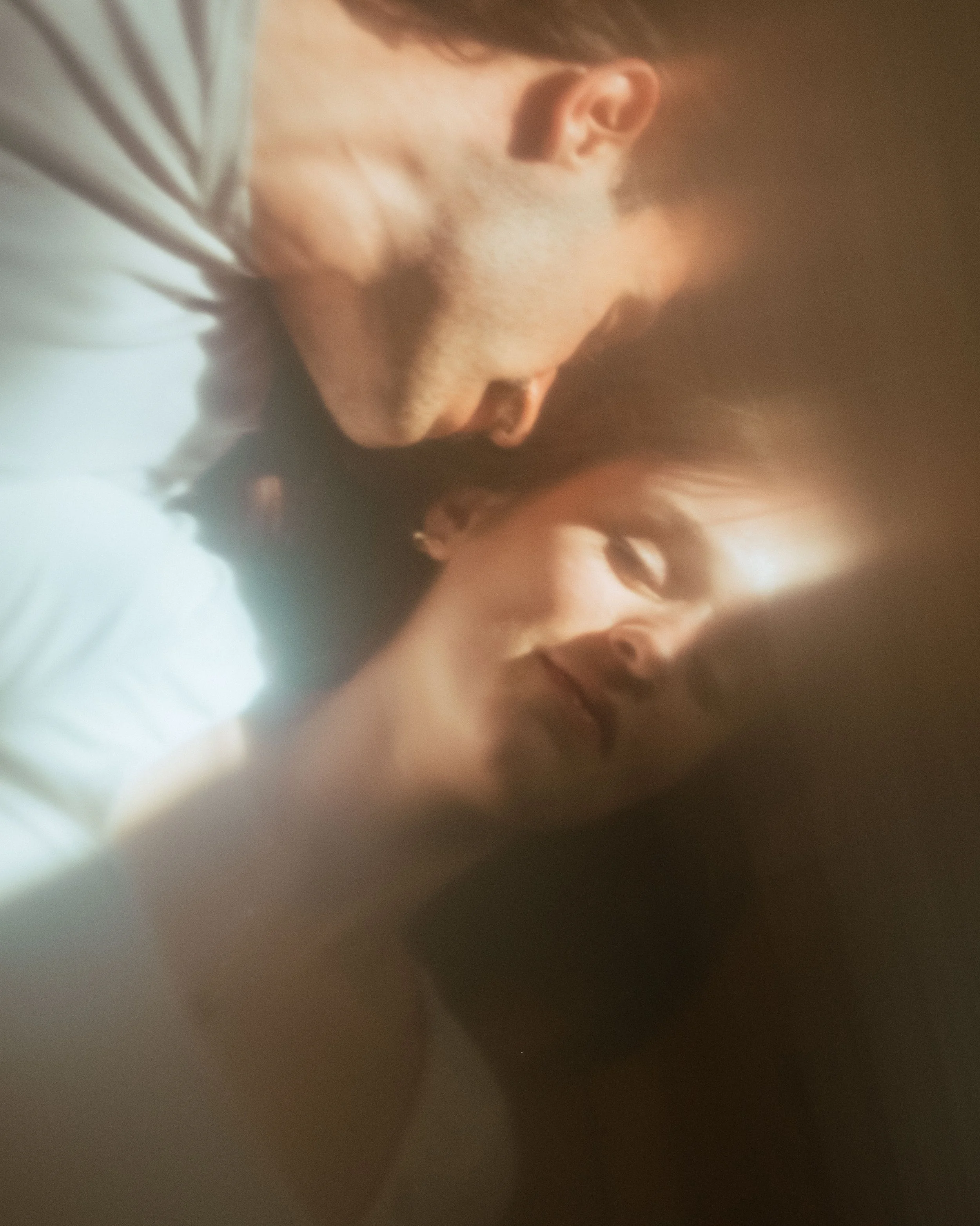 Close-up of a man and woman lying on their sides with their eyes closed, peaceful and intimate.