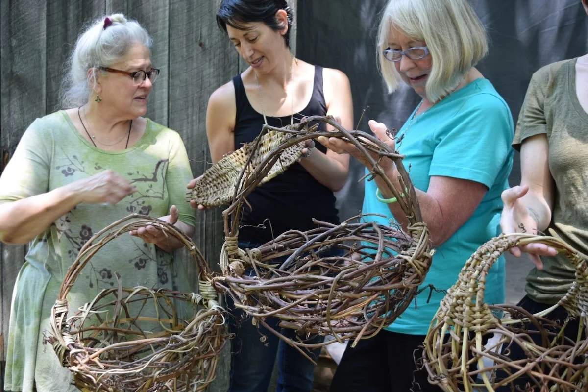three women examining random weave grapevine baskets