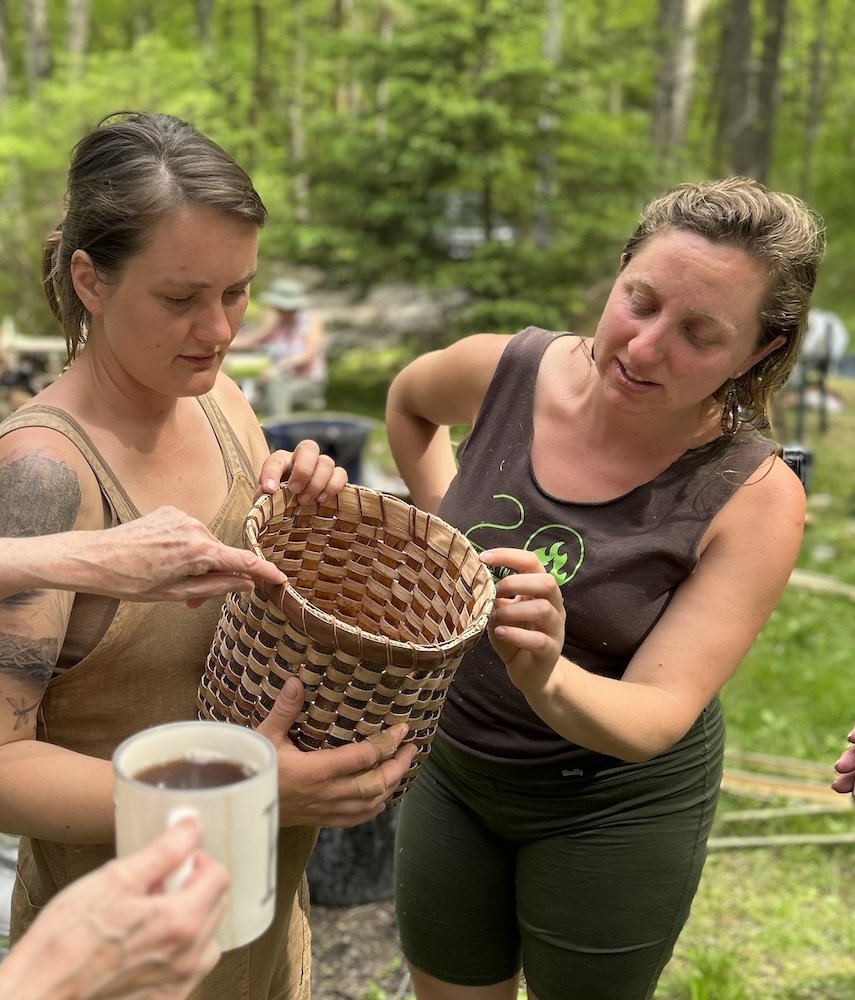 two women examining a woven bark basket