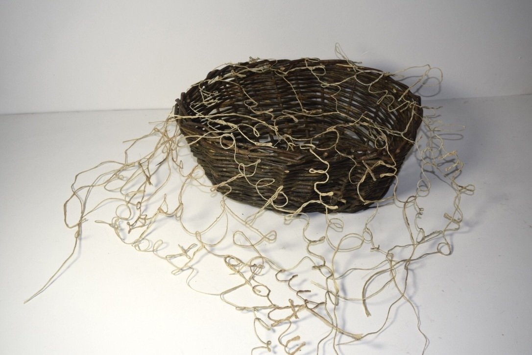 a willow basket with fiber script draped over it in sculptural form