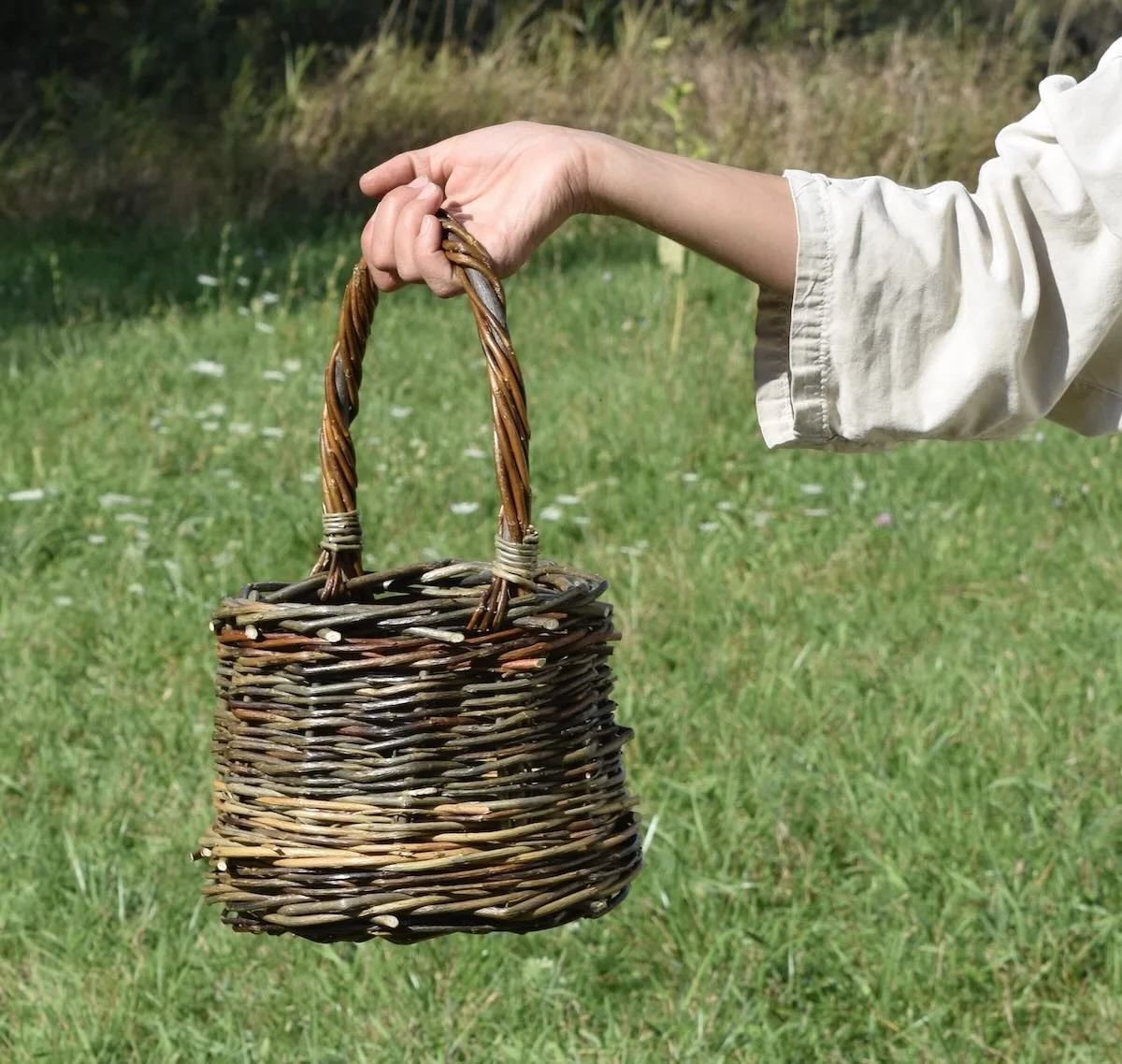 a hand holding a woven willow basket