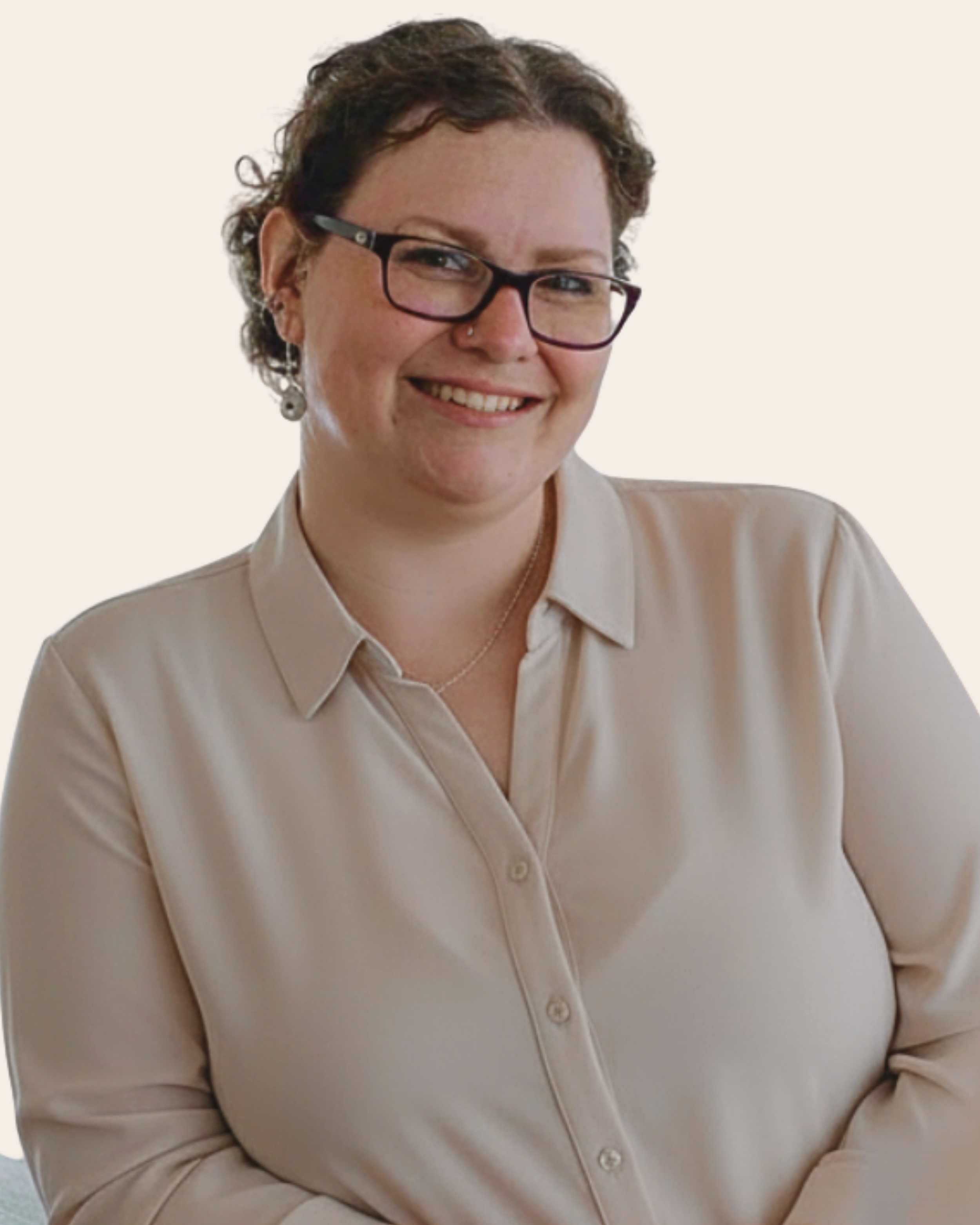 A woman with short curly hair, wearing glasses, earrings, a nose piercing, and a beige button-up shirt, smiling at the camera.