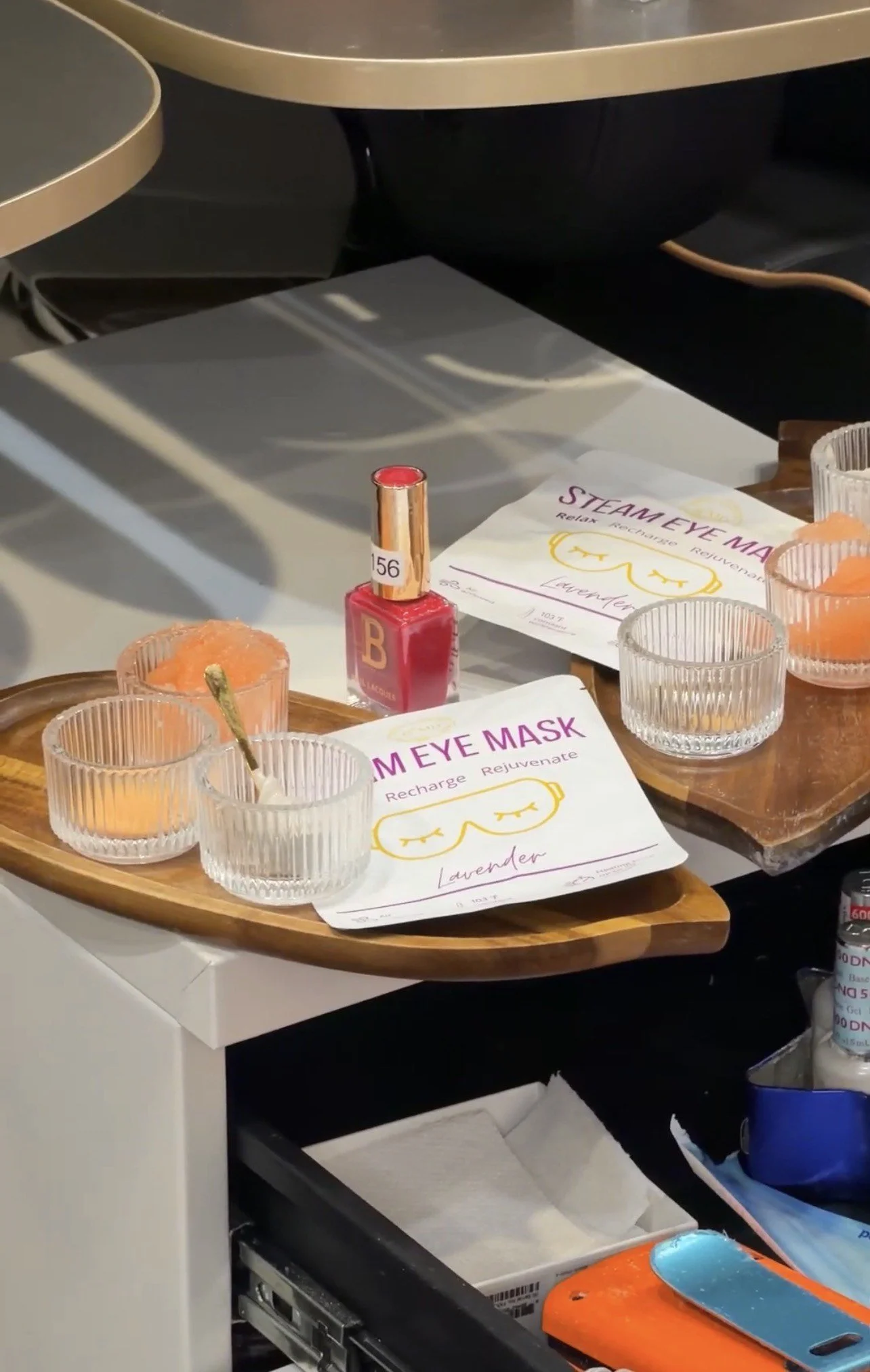 Salon setup with lavender-scented aroma therapy items, including candles, a red nail polish bottle, lavender eye masks, and informational sheets about eye masks.