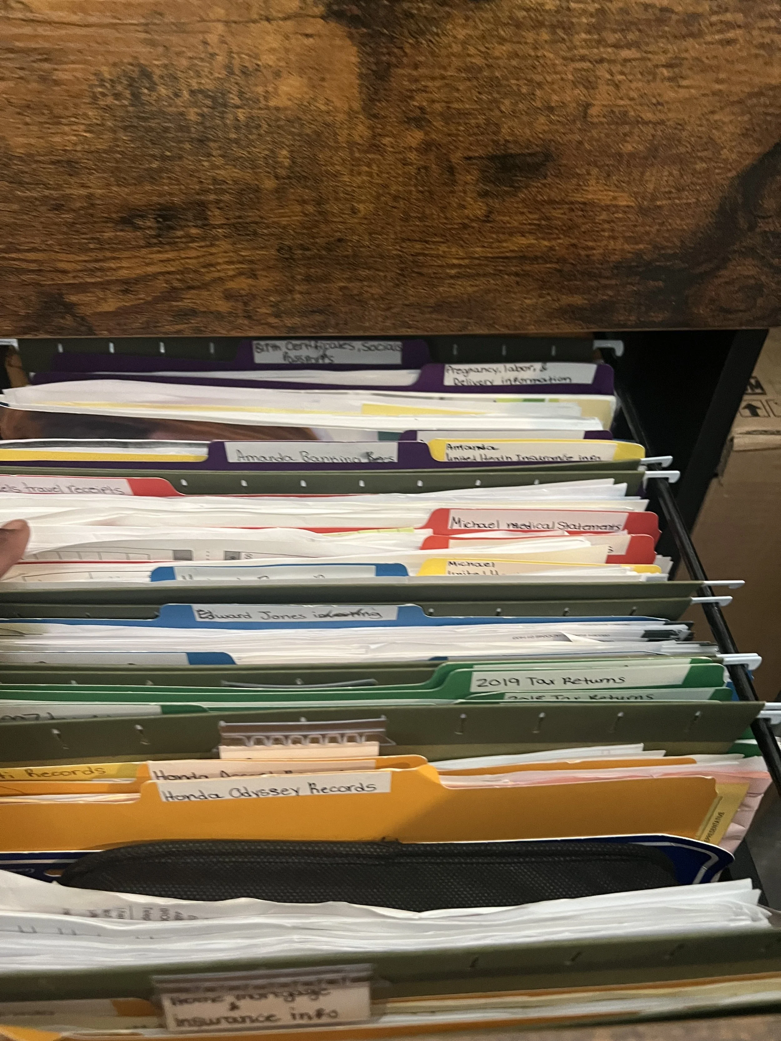 Organized file folders in a black filing drawer labeled with various topics and names such as 'Amanda Running Rec,' 'Edward Jones investments,' and 'Honda Odyssey Records.'