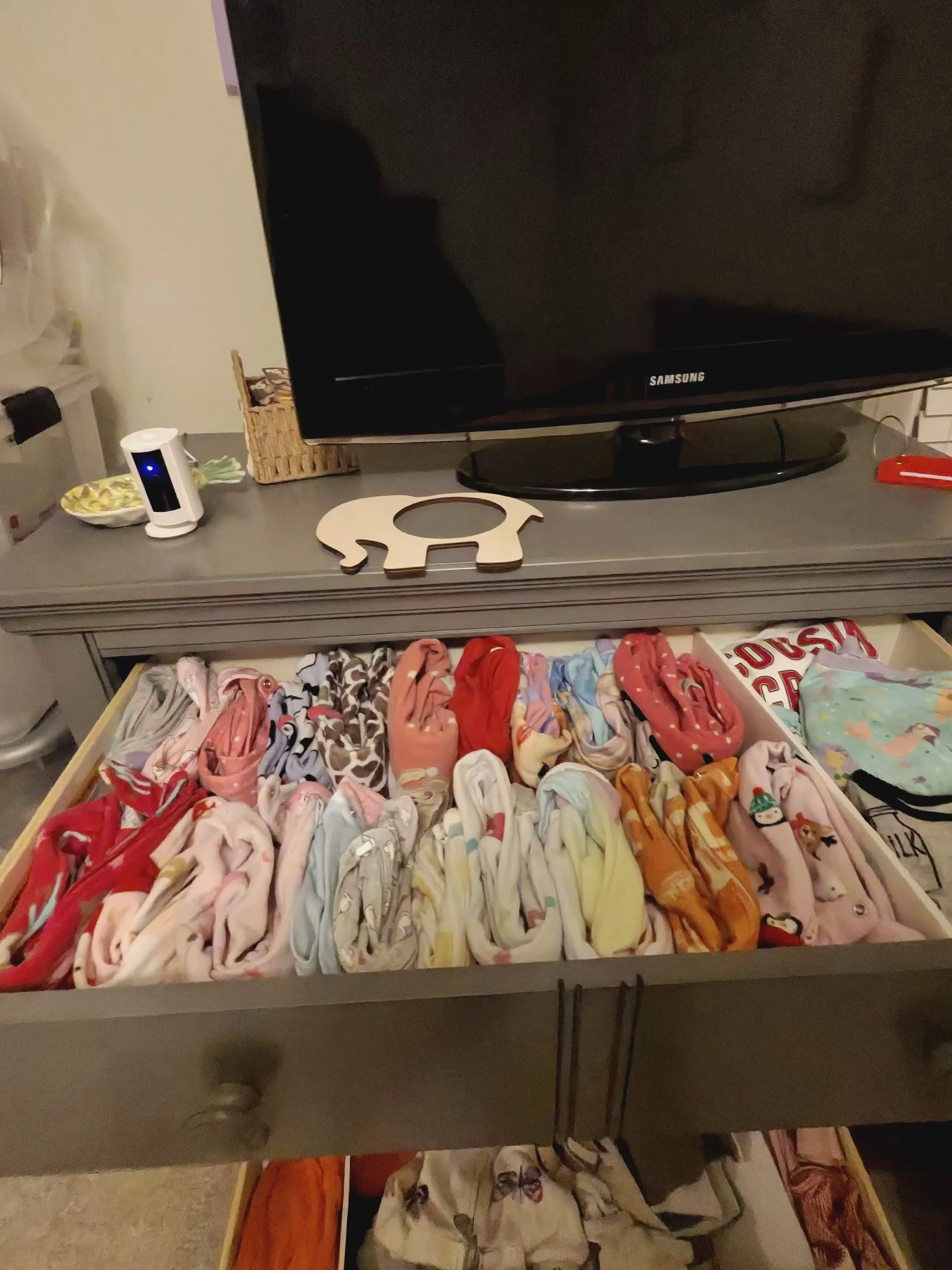 Open drawer filled with colorful folded baby or children's socks and clothing.