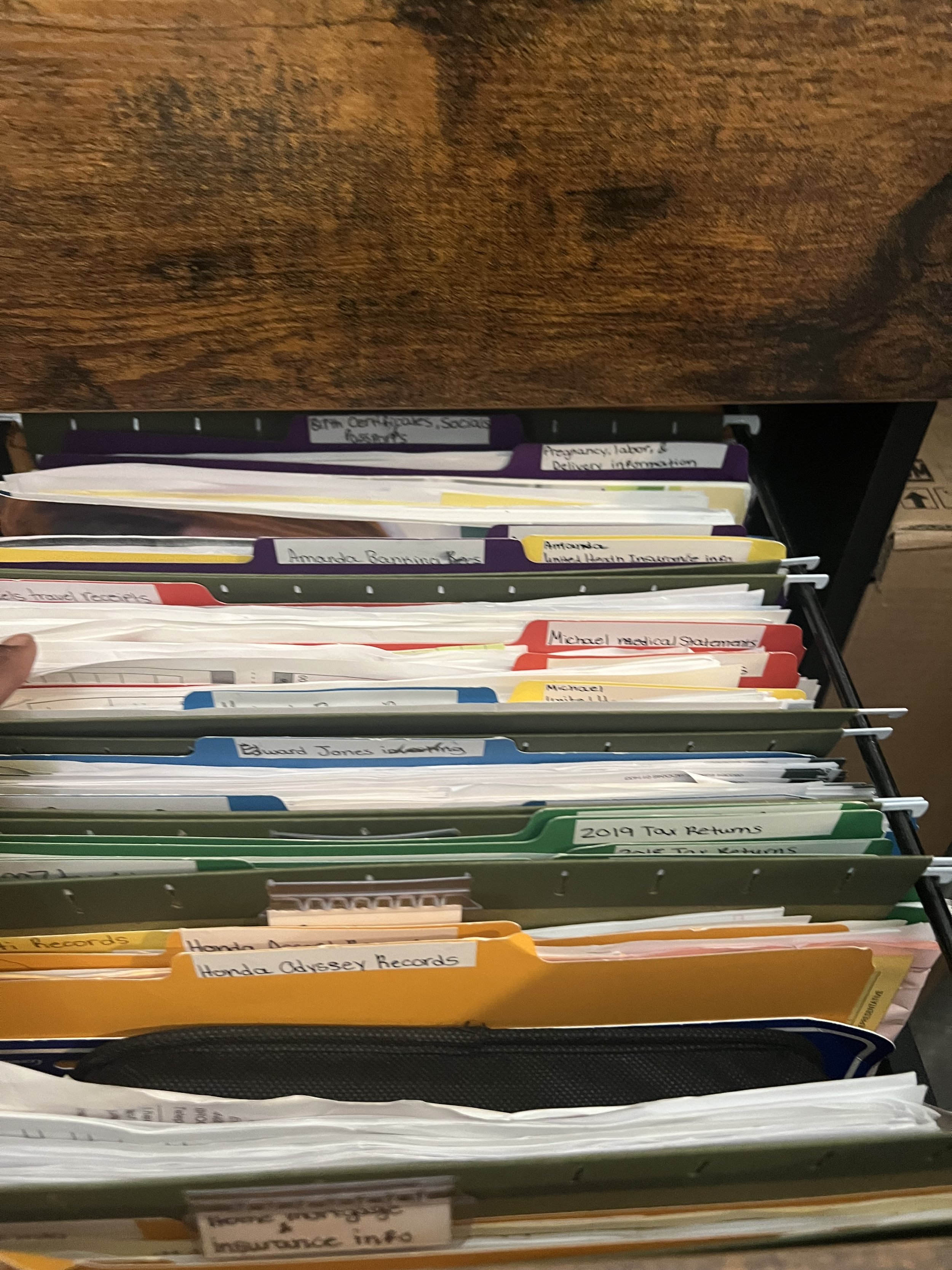 A file cabinet drawer filled with organized folders labeled with names and topics.