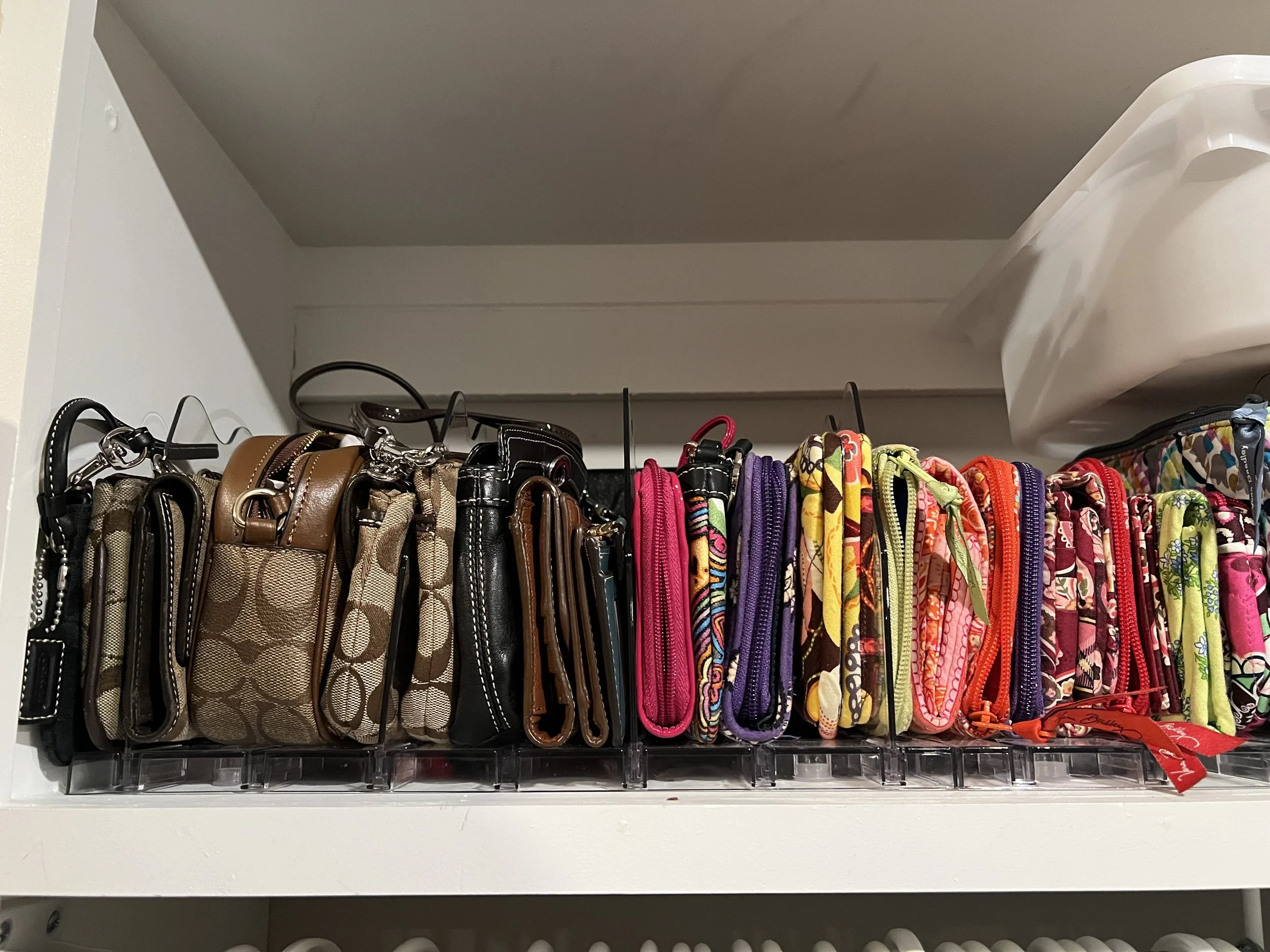 Organized colorful wallets and purses on a clear plastic tray. 