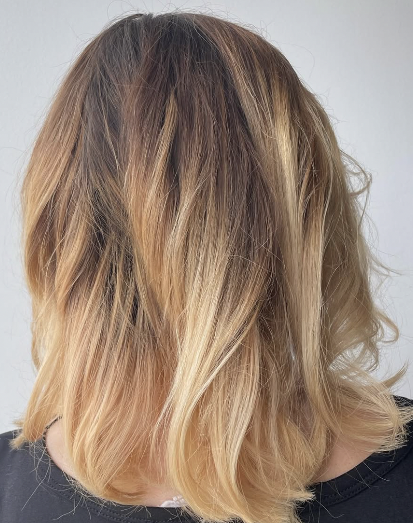 Medium blonde hair styled in loose waves.