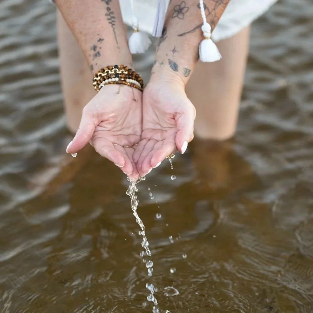 Hands holding water during a reflective New Day Vibes practice