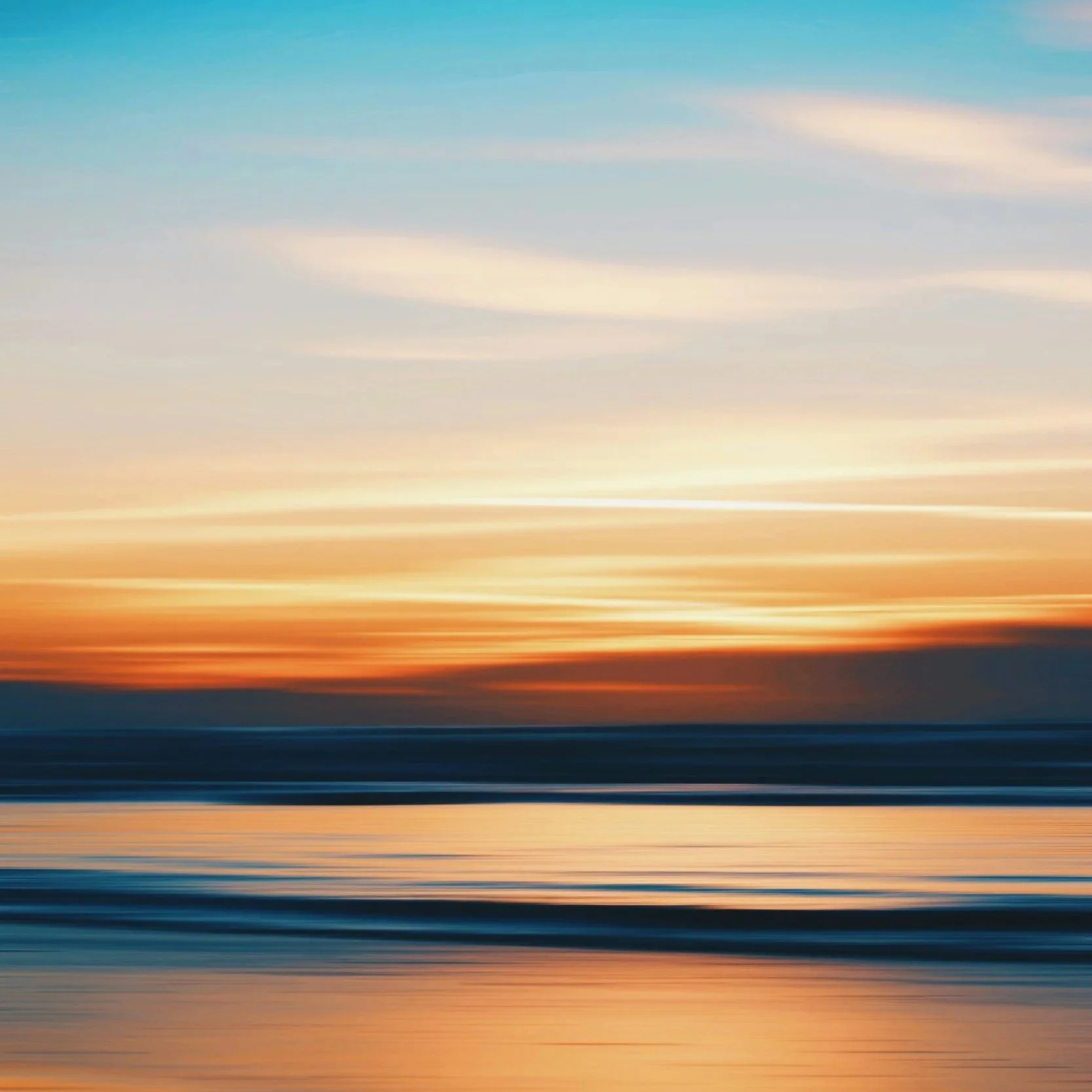 Colorful sunset over the ocean with reflected sky colors on the water, with blurred motion.