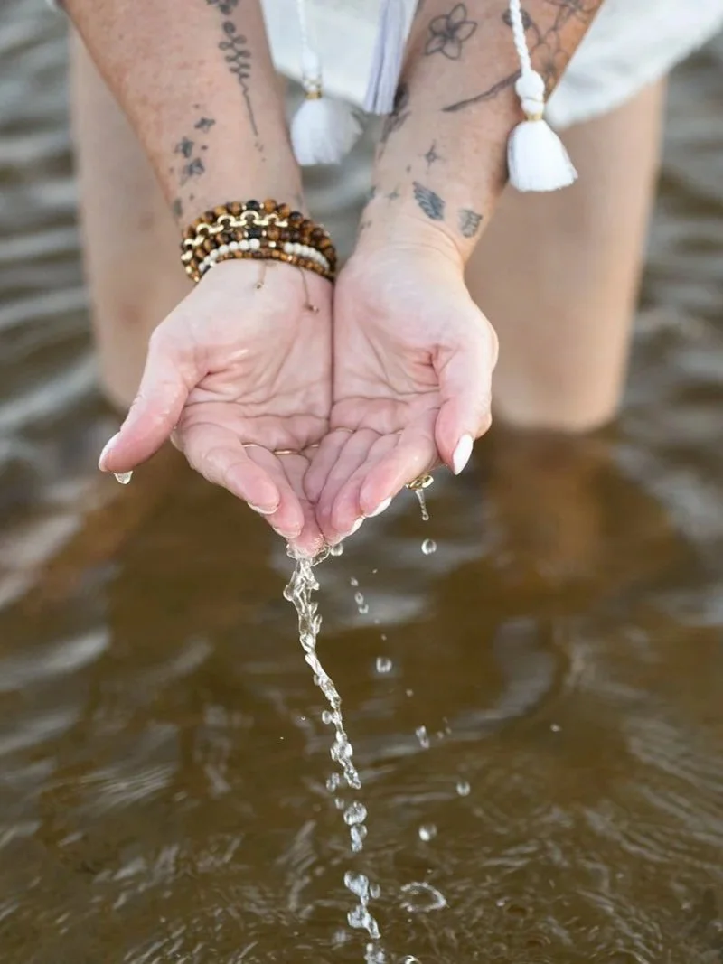 Hands holding water during a reflective New Day Vibes practice