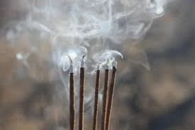 Burning incense sticks releasing fragrant smoke for ritual and meditation