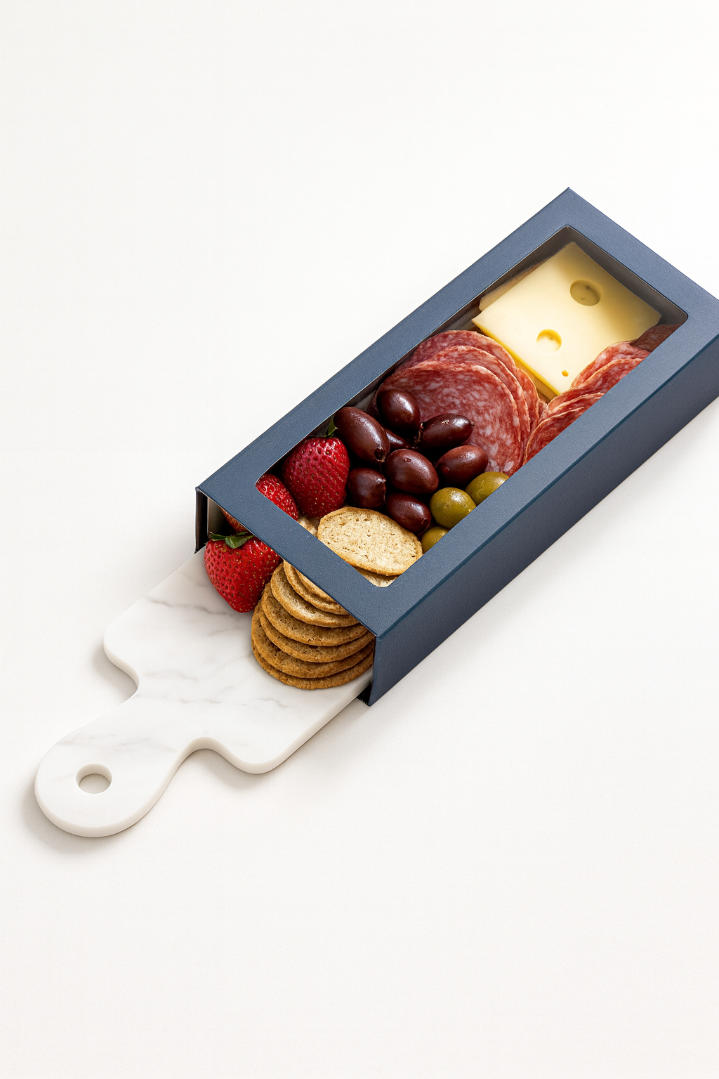 Cheese, strawberries, grapes, strawberries, salami, crackers, and olives in a rectangular box with a handle