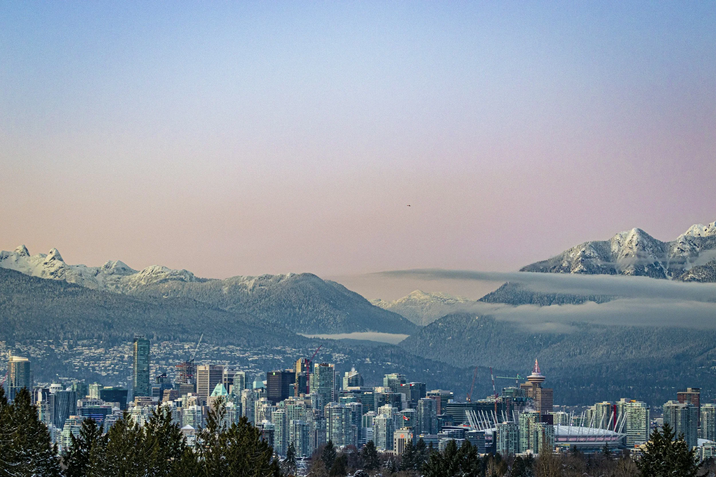 Vancouver city skyline at sunset, showcasing downtown buildings and mountains in the background
