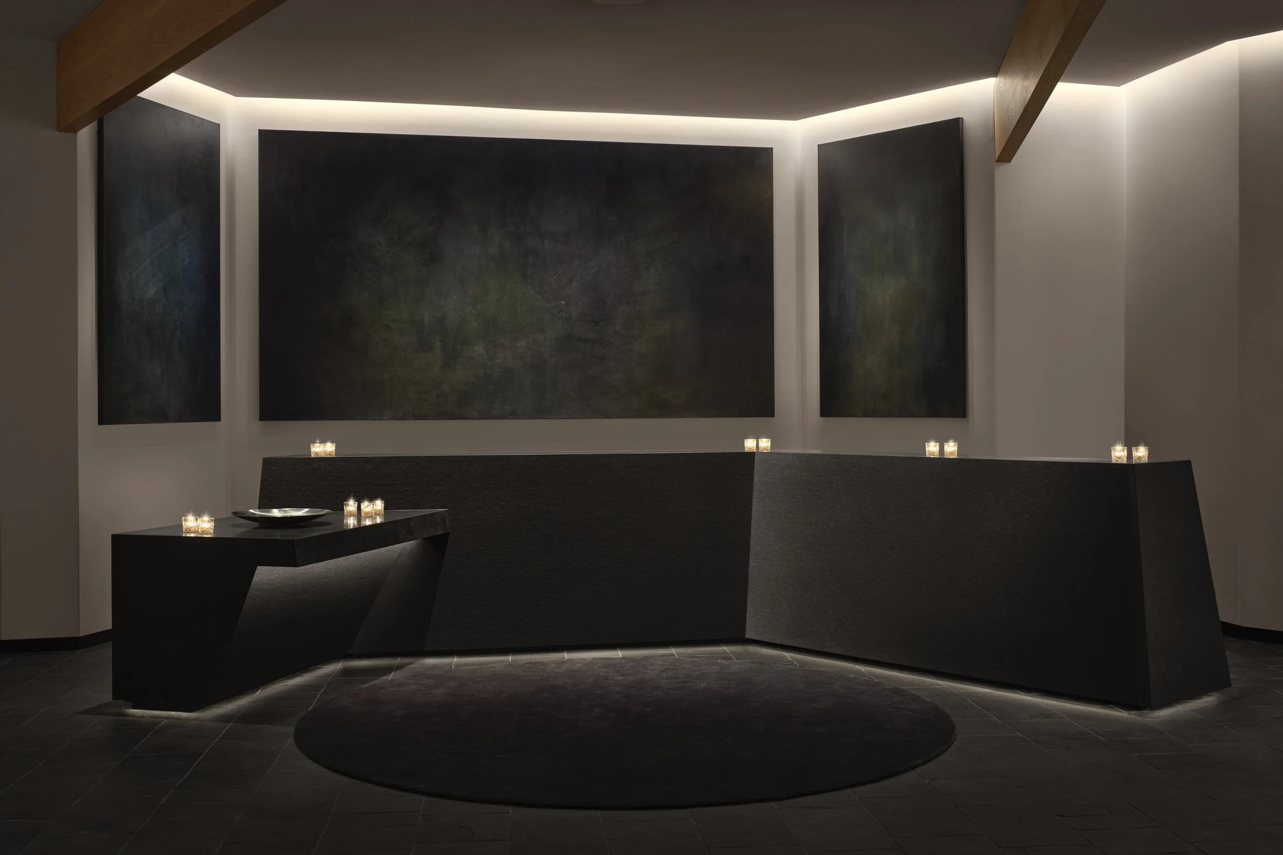 Modern interior with black furniture, dark wall art, candles, and subtle lighting.