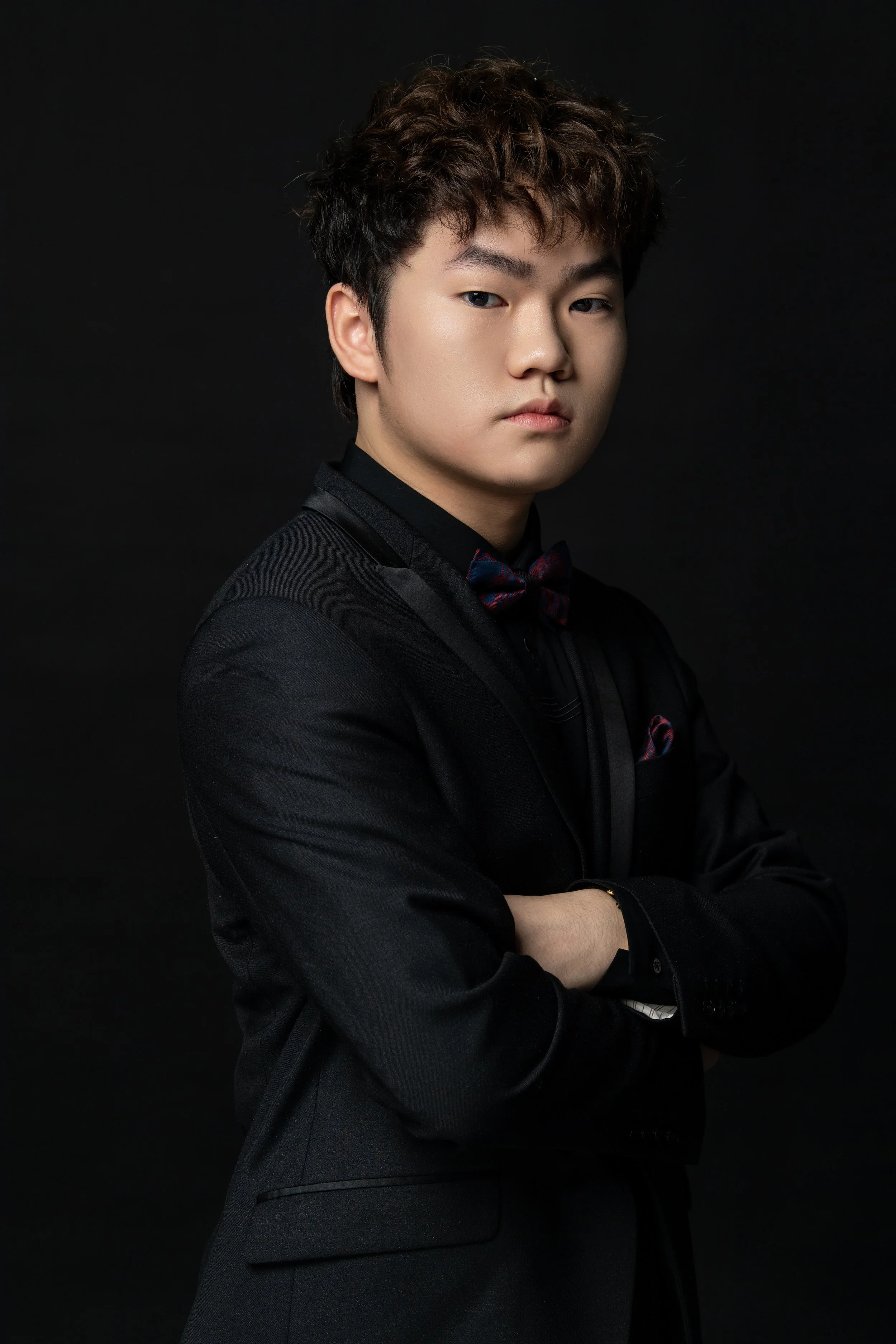 Hao Rao, pianist, formal portrait in a black tuxedo with bow tie.